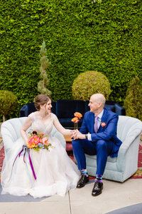 bride and groom sitting at colorful lounge furniture