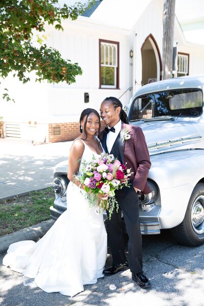 fallback shared on Invalid Date | african american couple wearing wedding attire and leaning against a vintage car