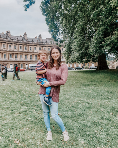fallback shared on Invalid Date | A mum holds her blonde boy in her arms in front of some historical houses