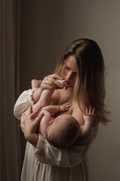fallback shared on Invalid Date | Mother cradling newborn in soft window light by Michigan maternity photographers