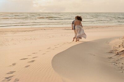 fallback shared on Invalid Date | Couple walking alone on the beach captured by Traverse City photographers

