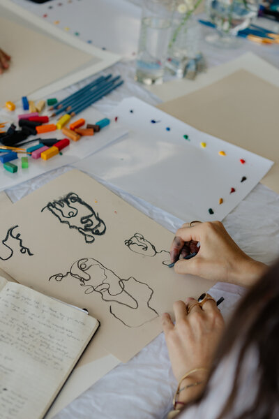 fallback shared on Invalid Date | Hands drawing with art supplies laid out in a creative workspace