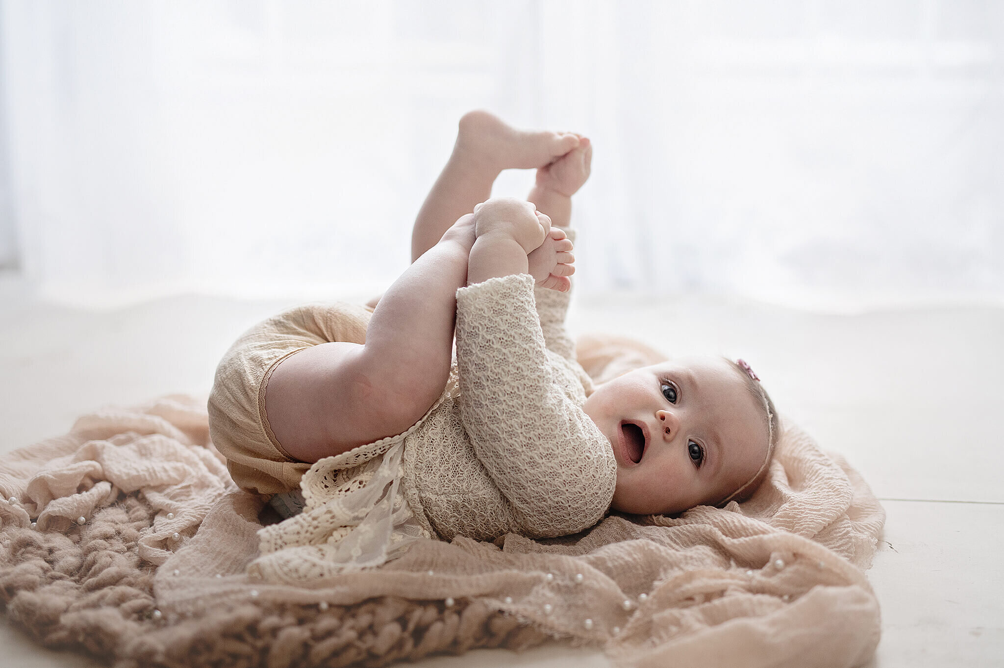 6 month old laying down and playing with her feet