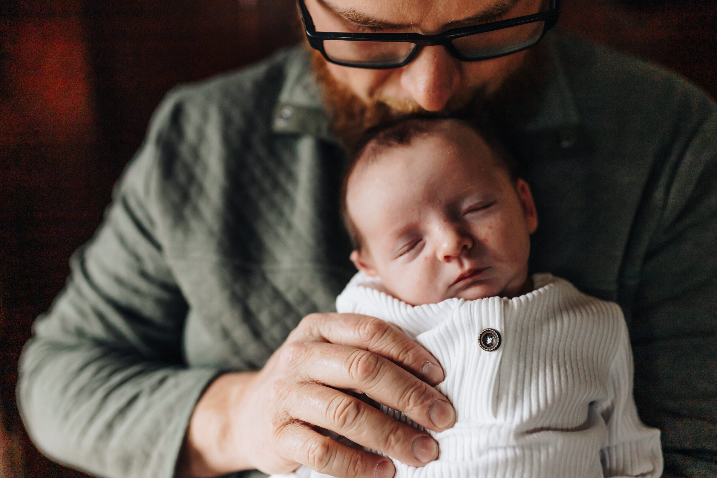 Dad Holds Newborn And Kisses Top Of Head