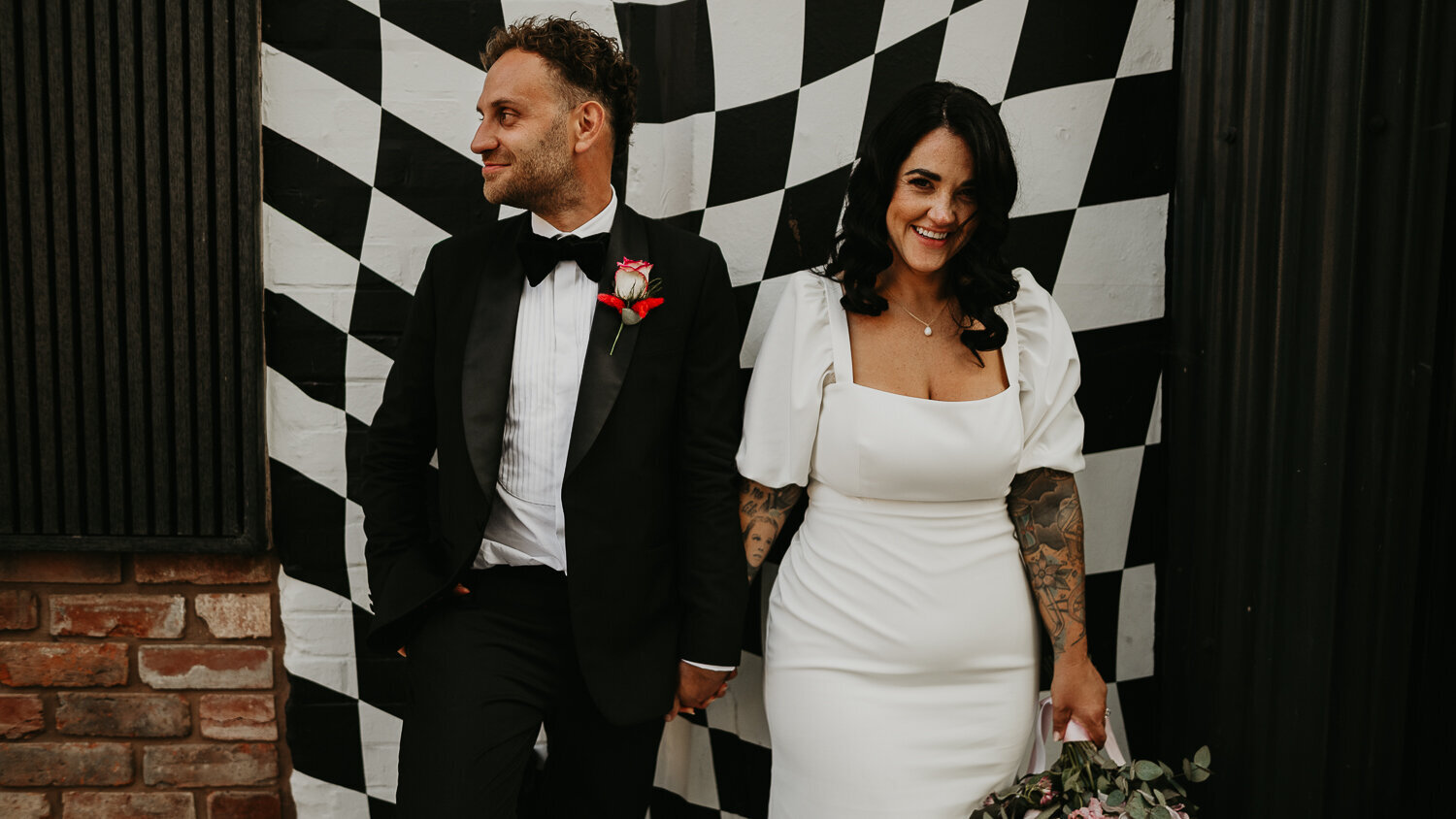 Tattooed Wedding couple stand in front of a checkered mural at The Shack Revolution in Hereford.