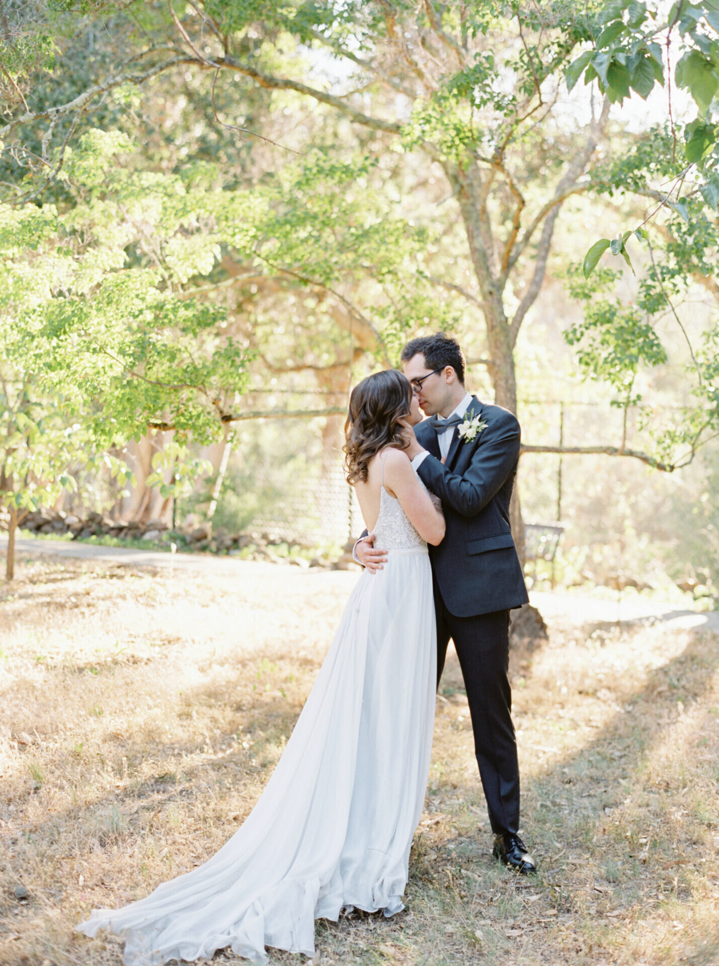 outdoor photo of bride and groom kissing in golden California garden