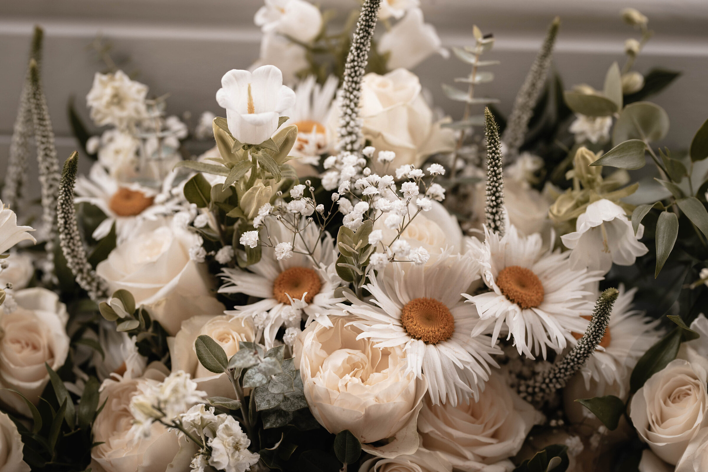 Close up of bridal bouquet filled with gypsophila, daisies, roses and eucalyptus