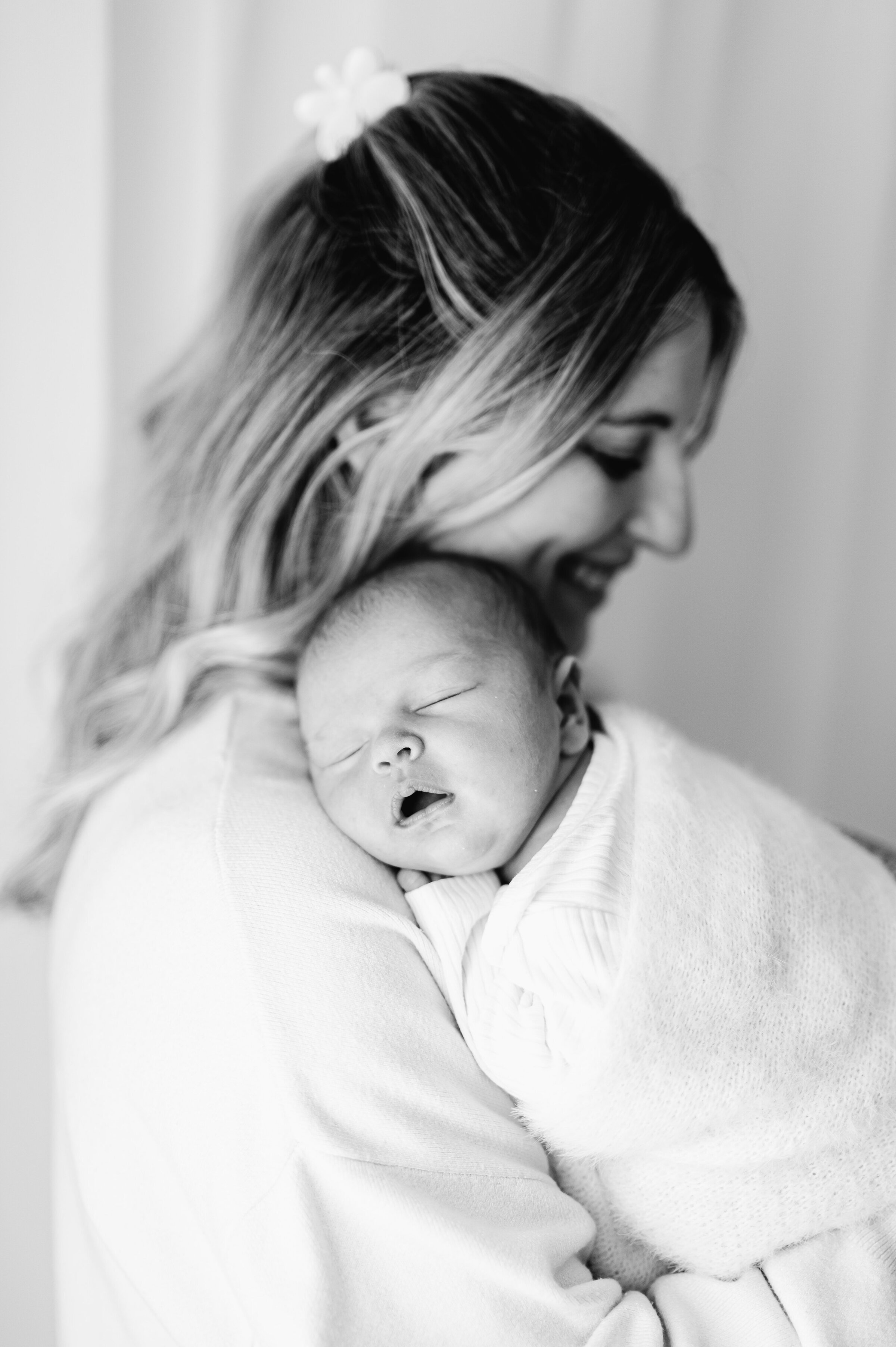 A newborn girl sleeping on her mothers shoulder at a photoshoot in Billingshurst