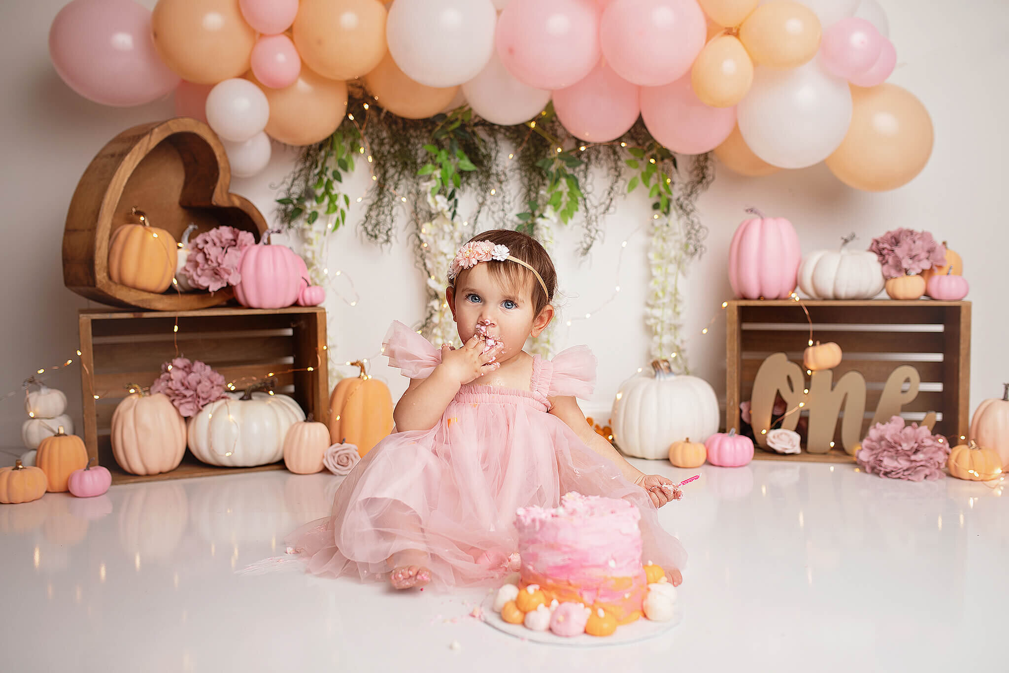 1 year old girl eating smash cake with pastel pumpkin theme