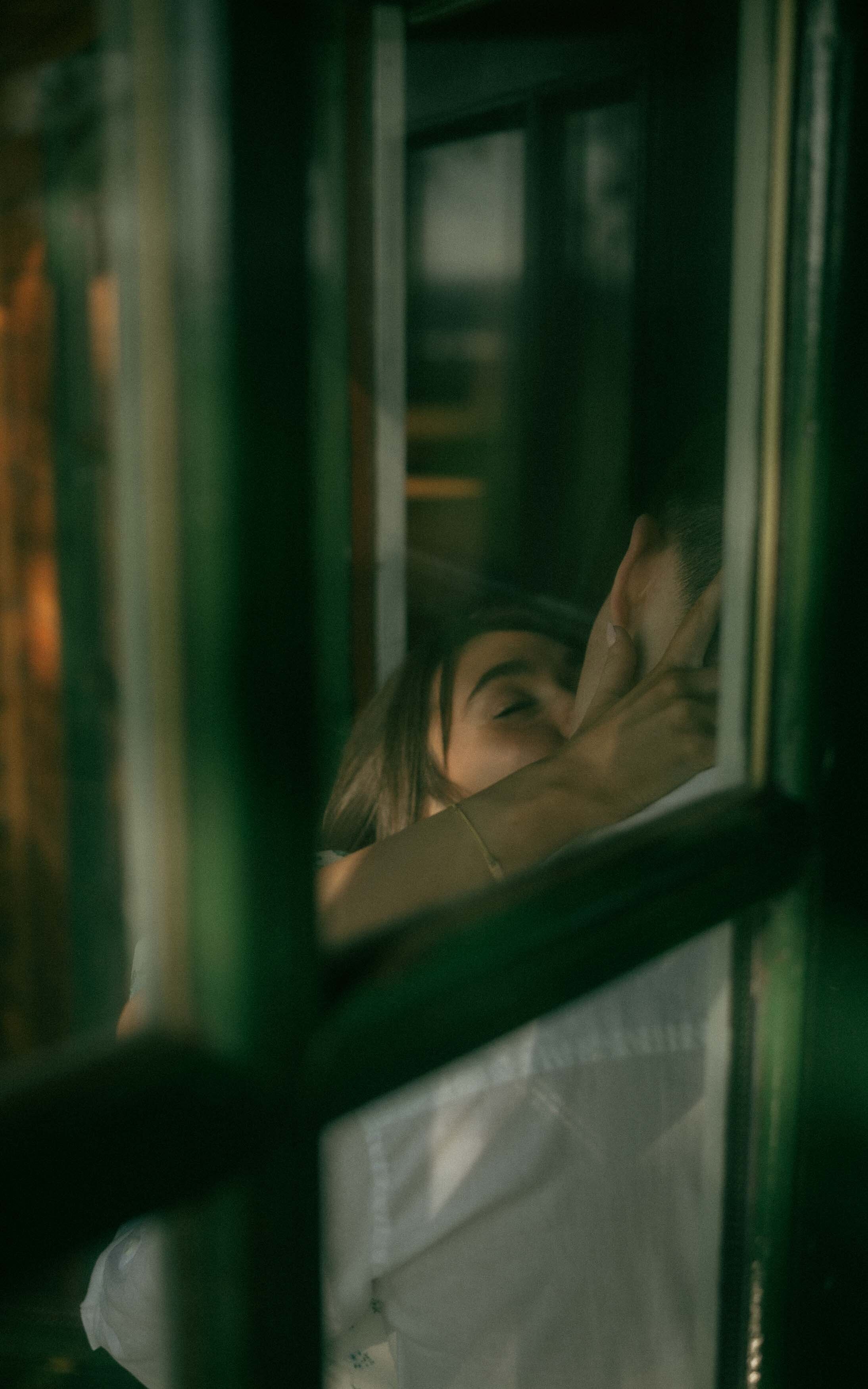 A romantic moment of a couple sharing a kiss next to a door, showcasing their love and connection in a simple yet intimate setting