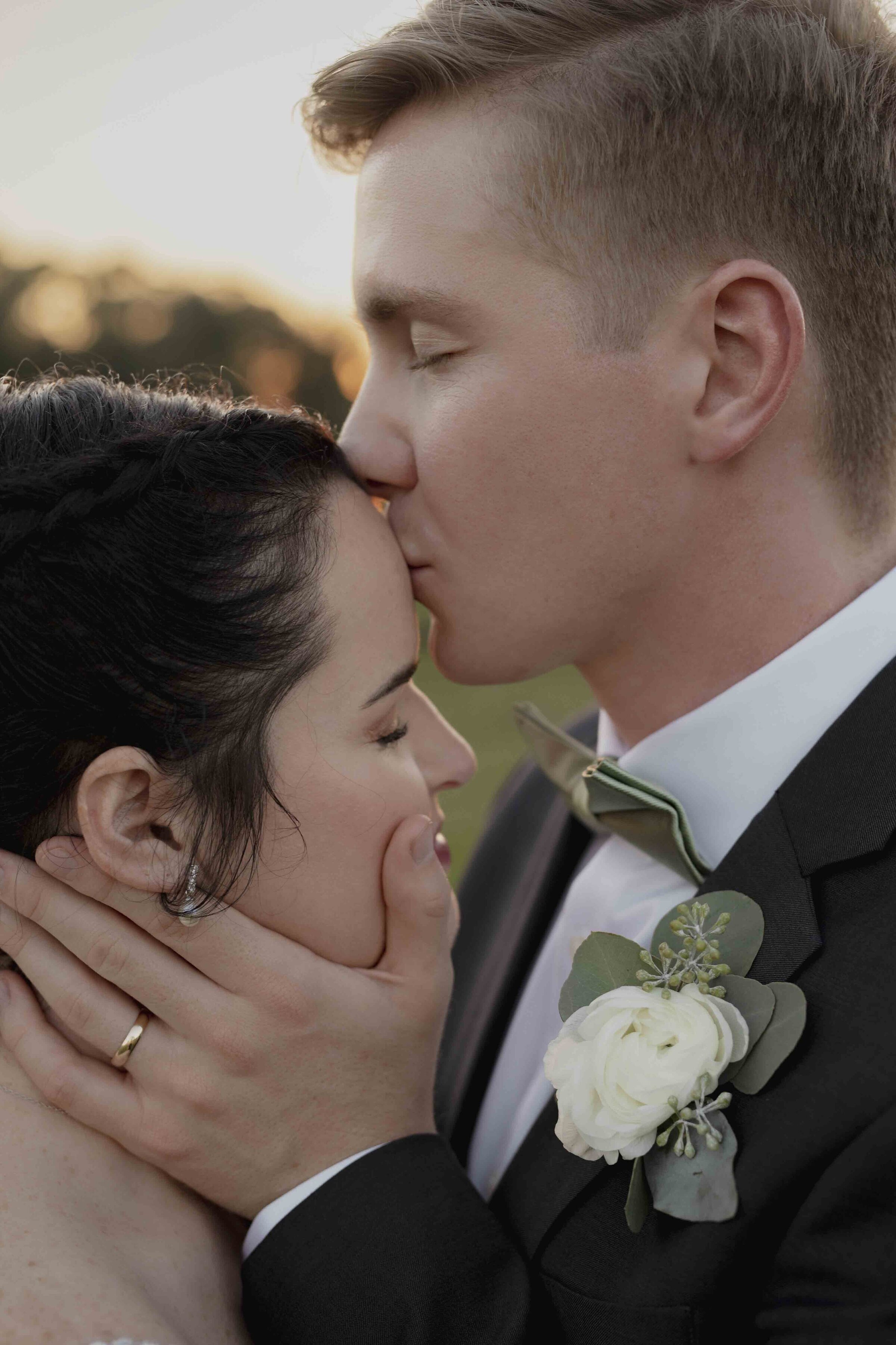 Groom kissing bride's forehead