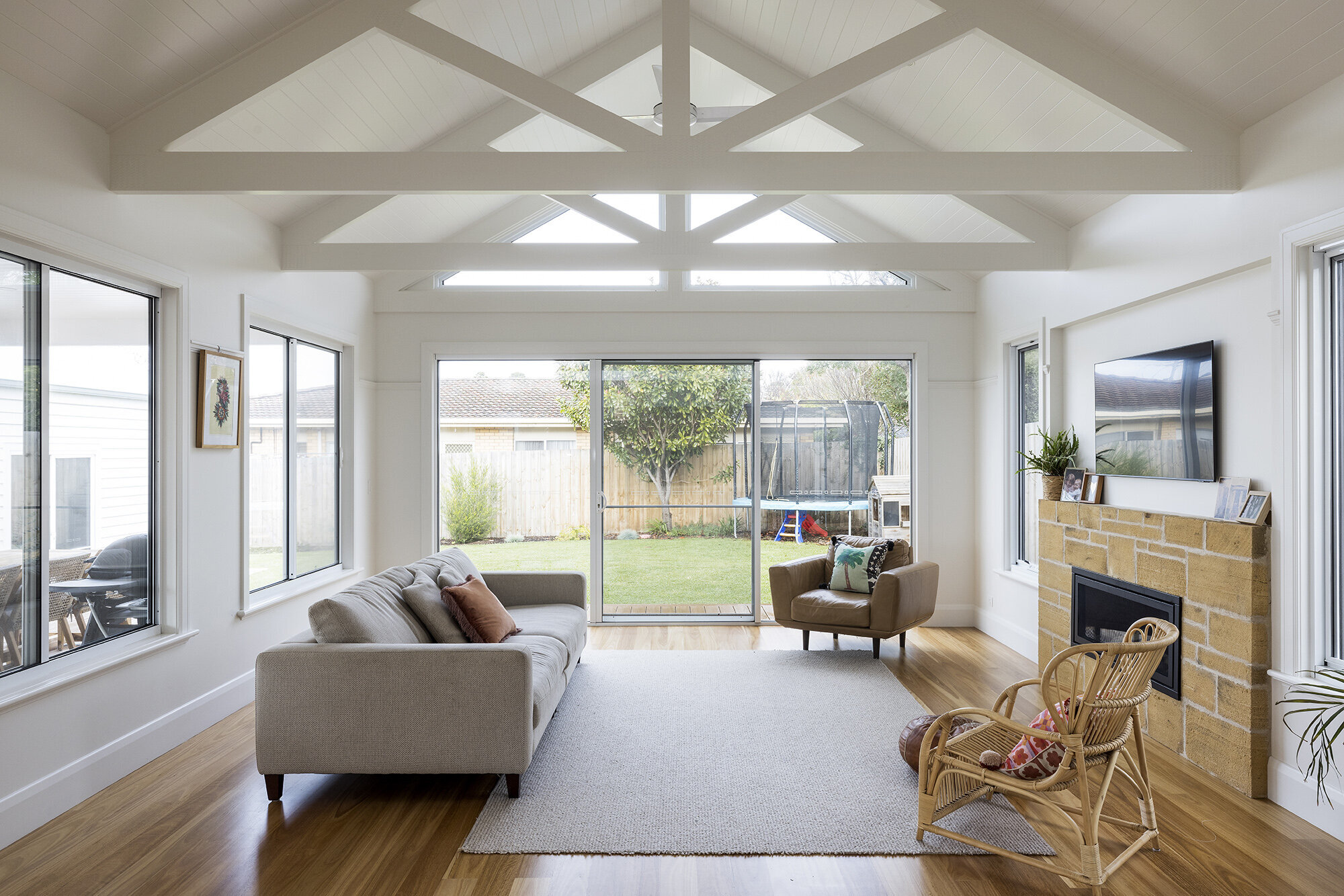 Lounge area with exposed white beams on pitched ceiling stone fireplace