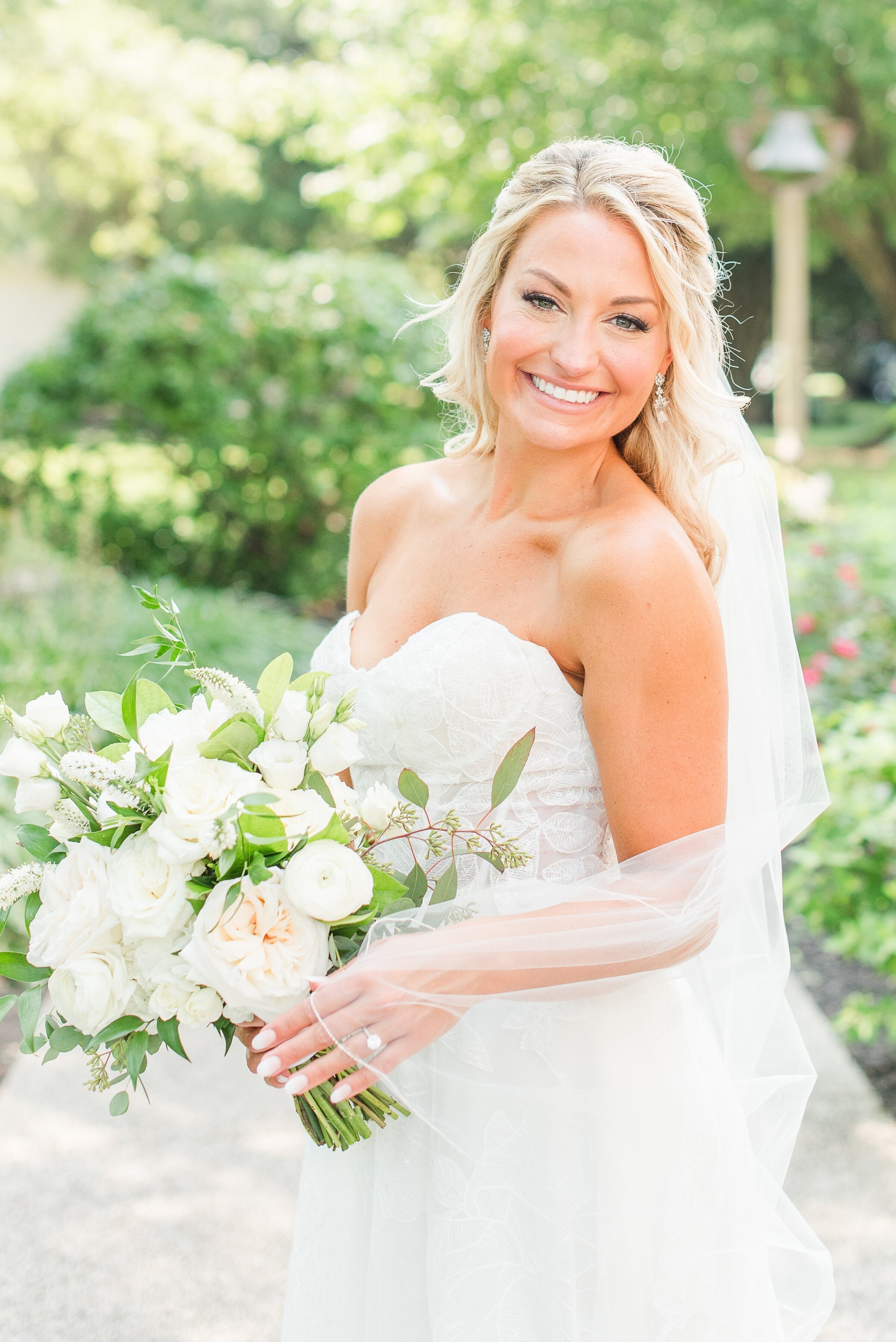 blonde bride holding her veil and bouquet on wedding day