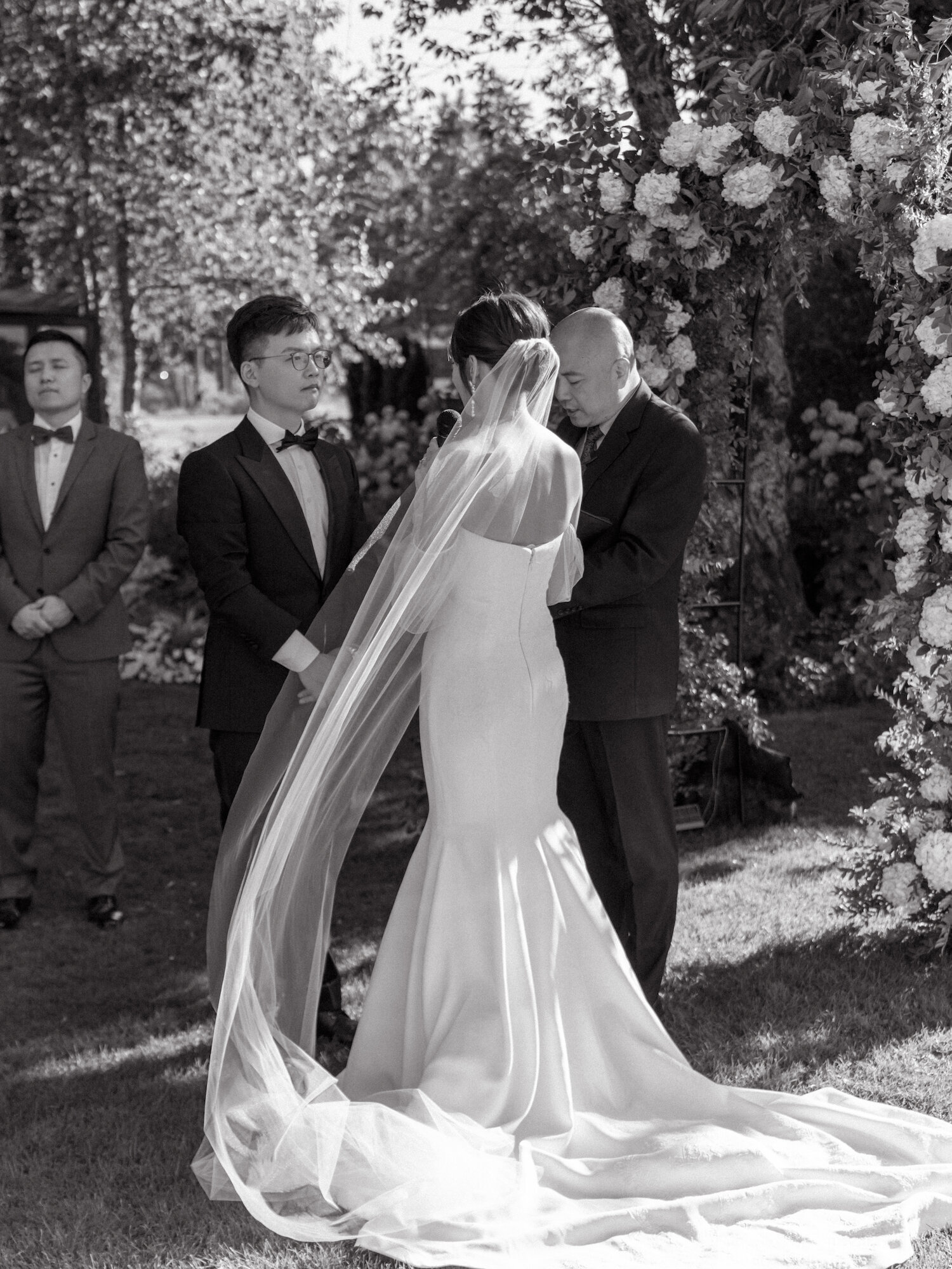 black and white photo of brides veil blowing in the wind at wedding ceremony