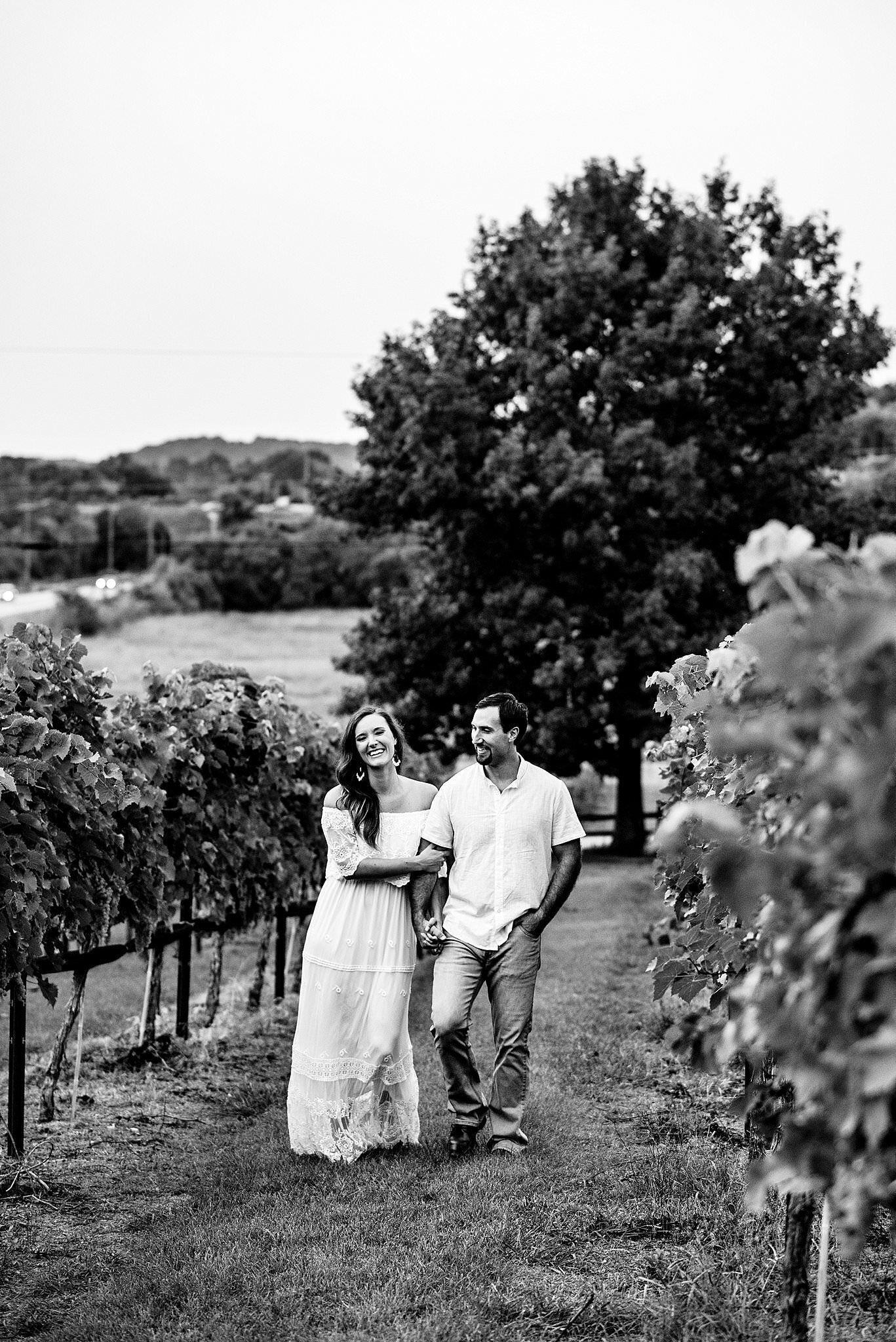 Black and White photo of couple strolling through the vineyards are in arm