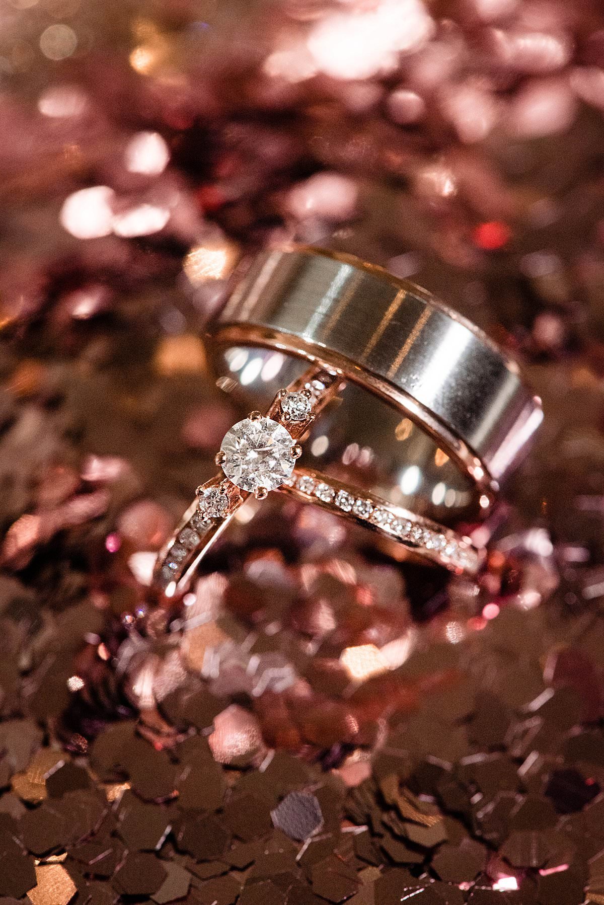 Brides rose gold wedding band and engagement ring and grooms copper band on top of rose gold glitter