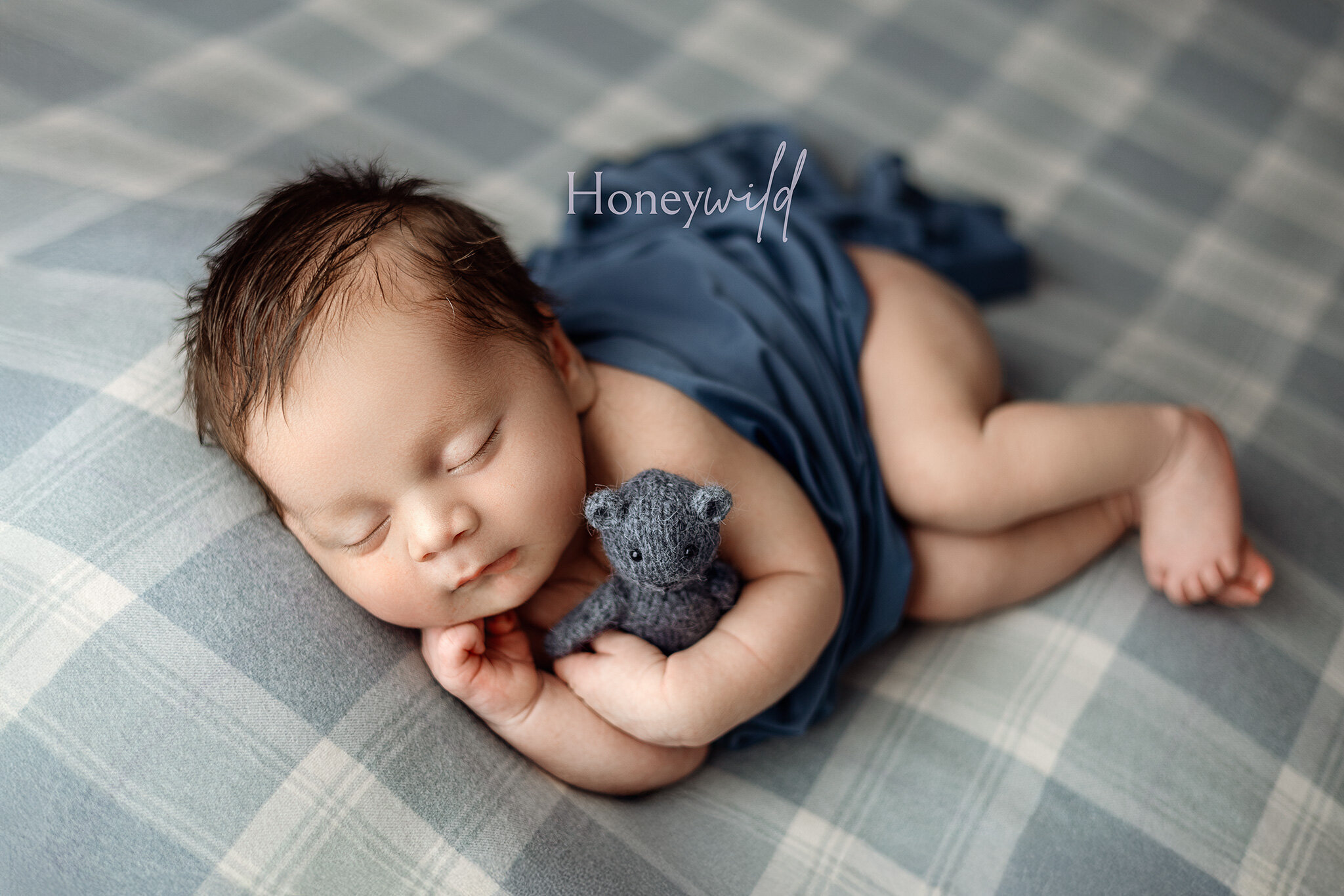 Grand Rapids newborn photographer captures baby sleeping on stomach wearing  bonnet on floral blanket