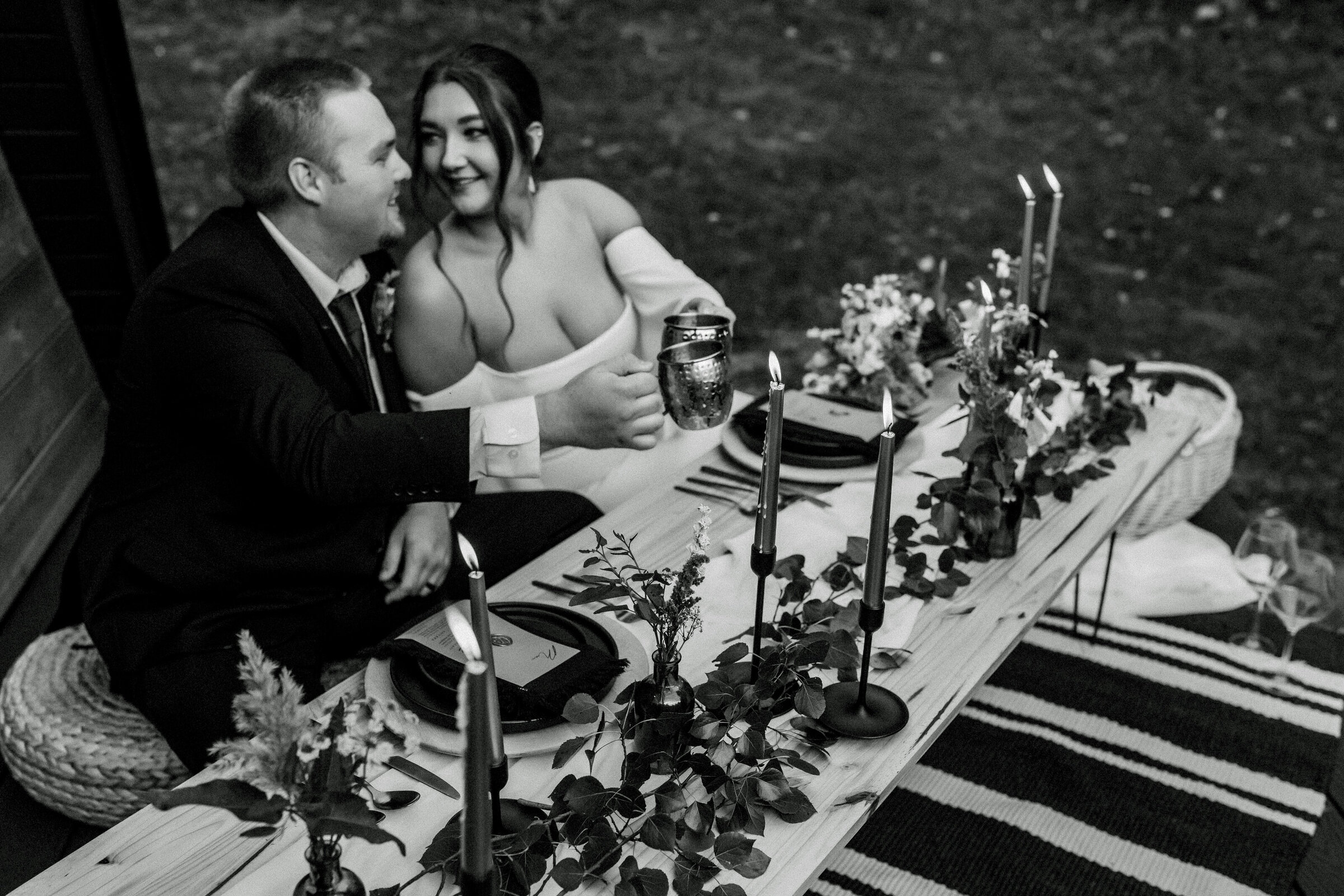 Black and white photo of couple at table eating at elopement
