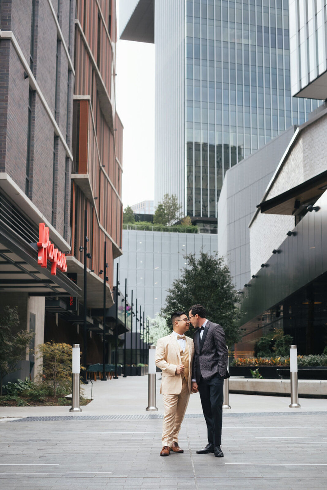 Same-sex wedding portrait of two grooms near the Pittman Hotel with a modern urban backdrop.