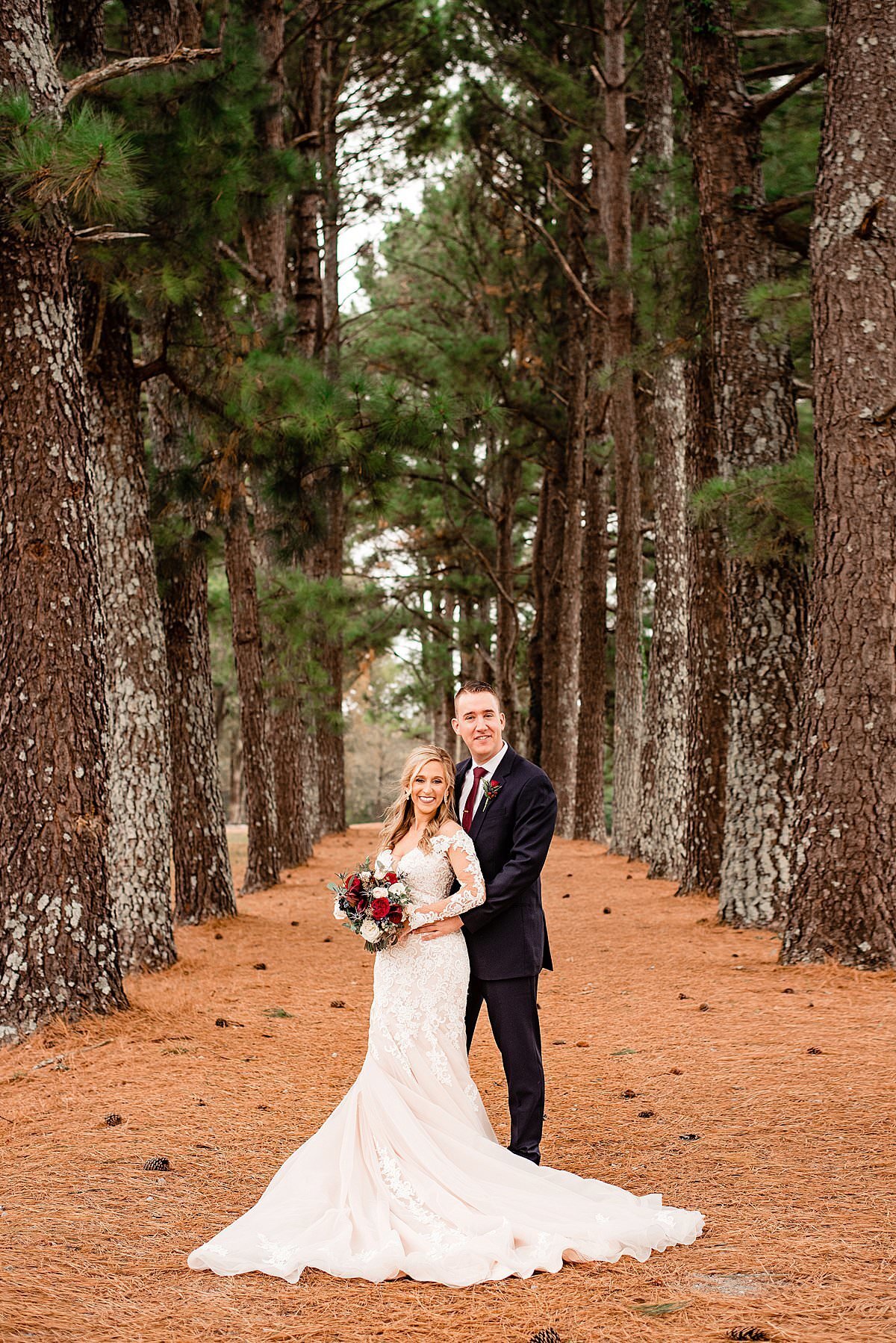 Portrait of Bride and groom standing in evergreen treeline at Rural Hill Farm, pine needles of ground surrounding them