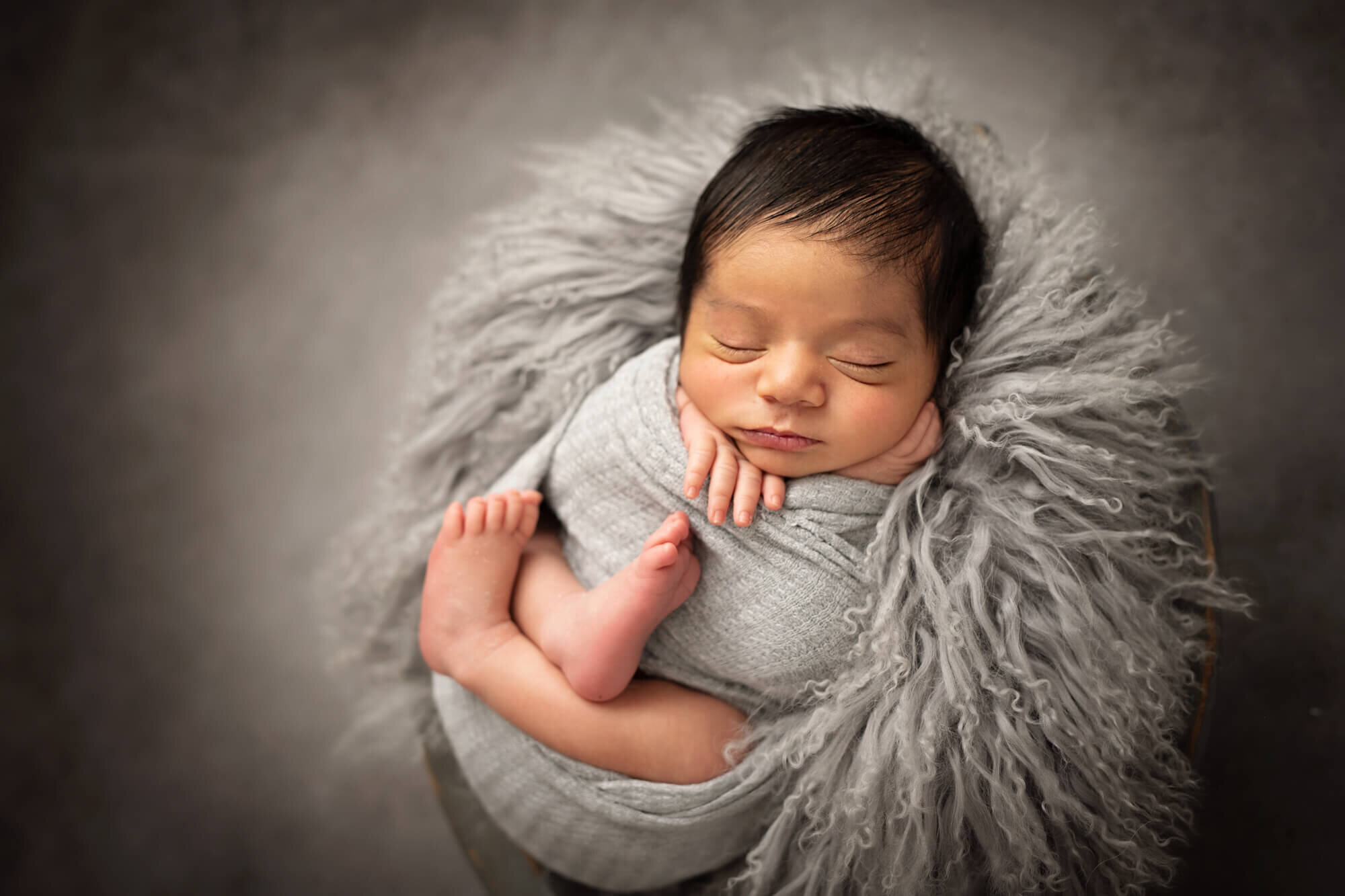 Sleeping baby in fur layer with grey wrap  feet showing