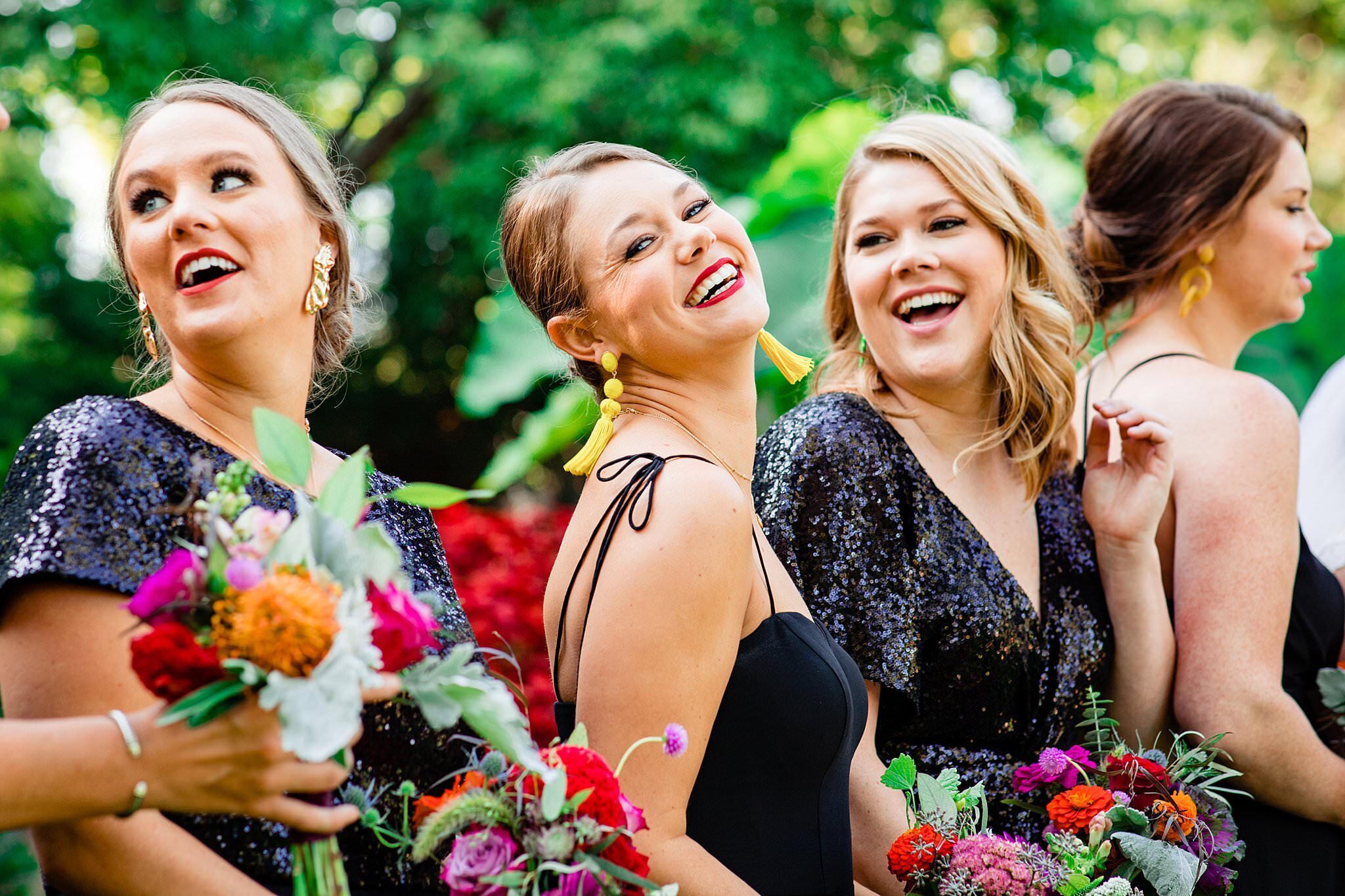 Bridesmaids wearing fancy black party dresses paired with bright bouquets and colorful earrings