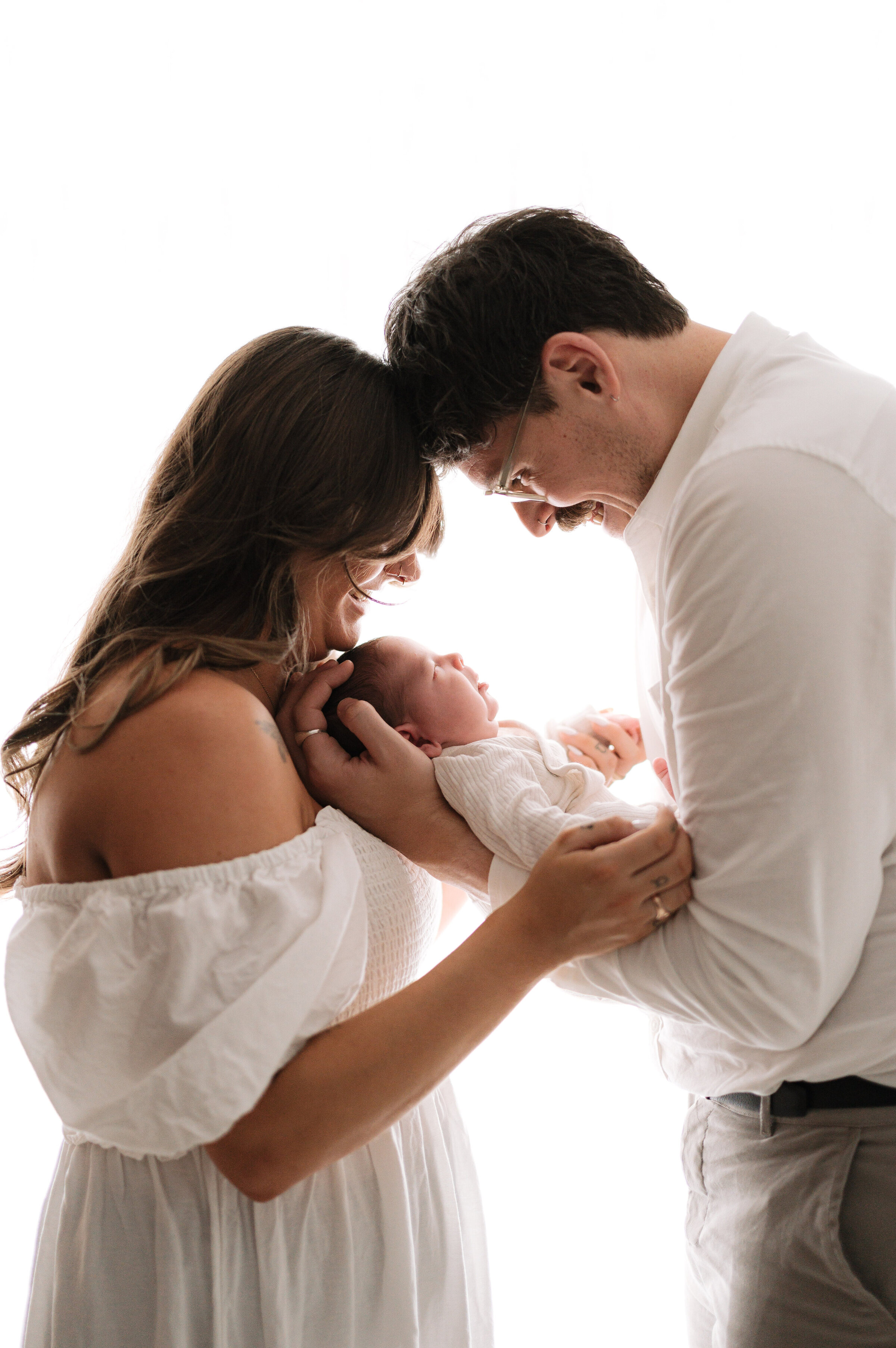Mother and father holding their newborn daughter in between them at a photoshoot in Billingshurst