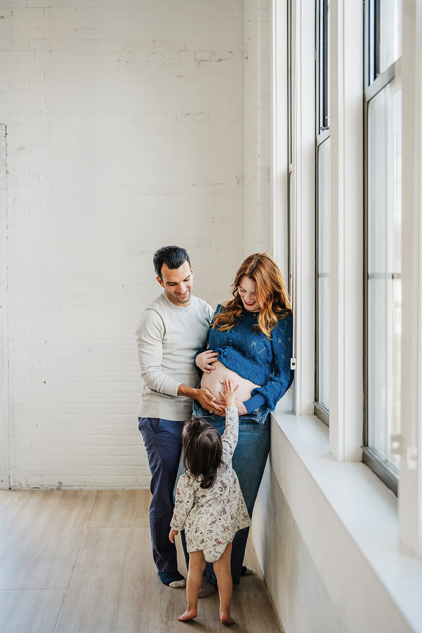 toddler daughter touches pregnant moms belly