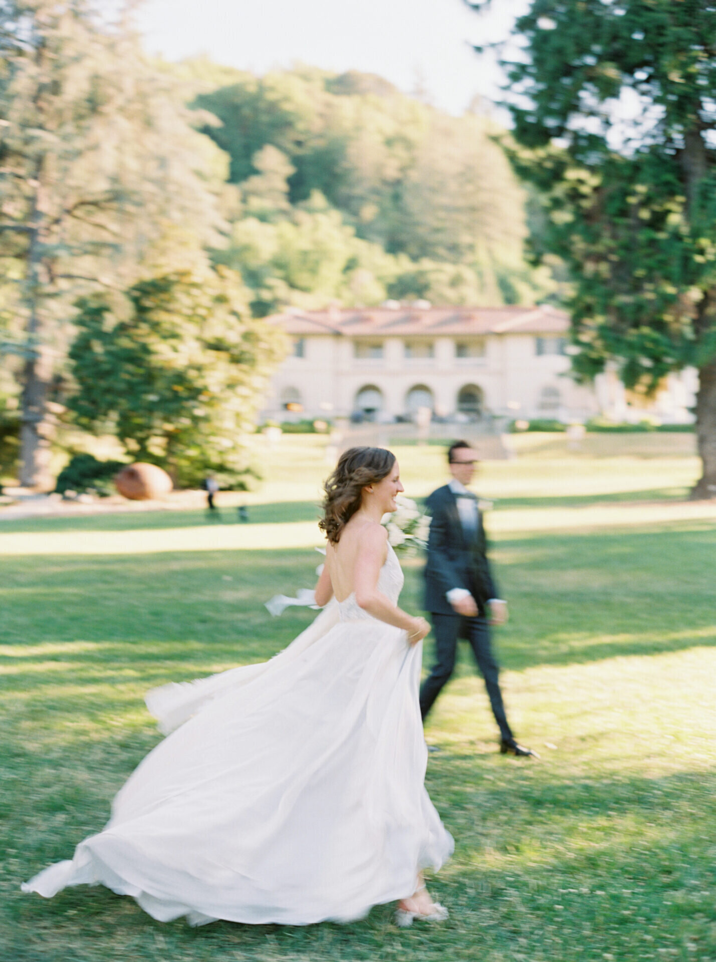 motion blur film photo of bride and groom running through the grass out front of CA Villa