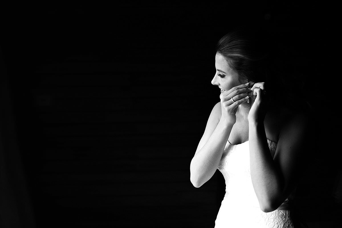 Black and White photo of bride putting her earrings in