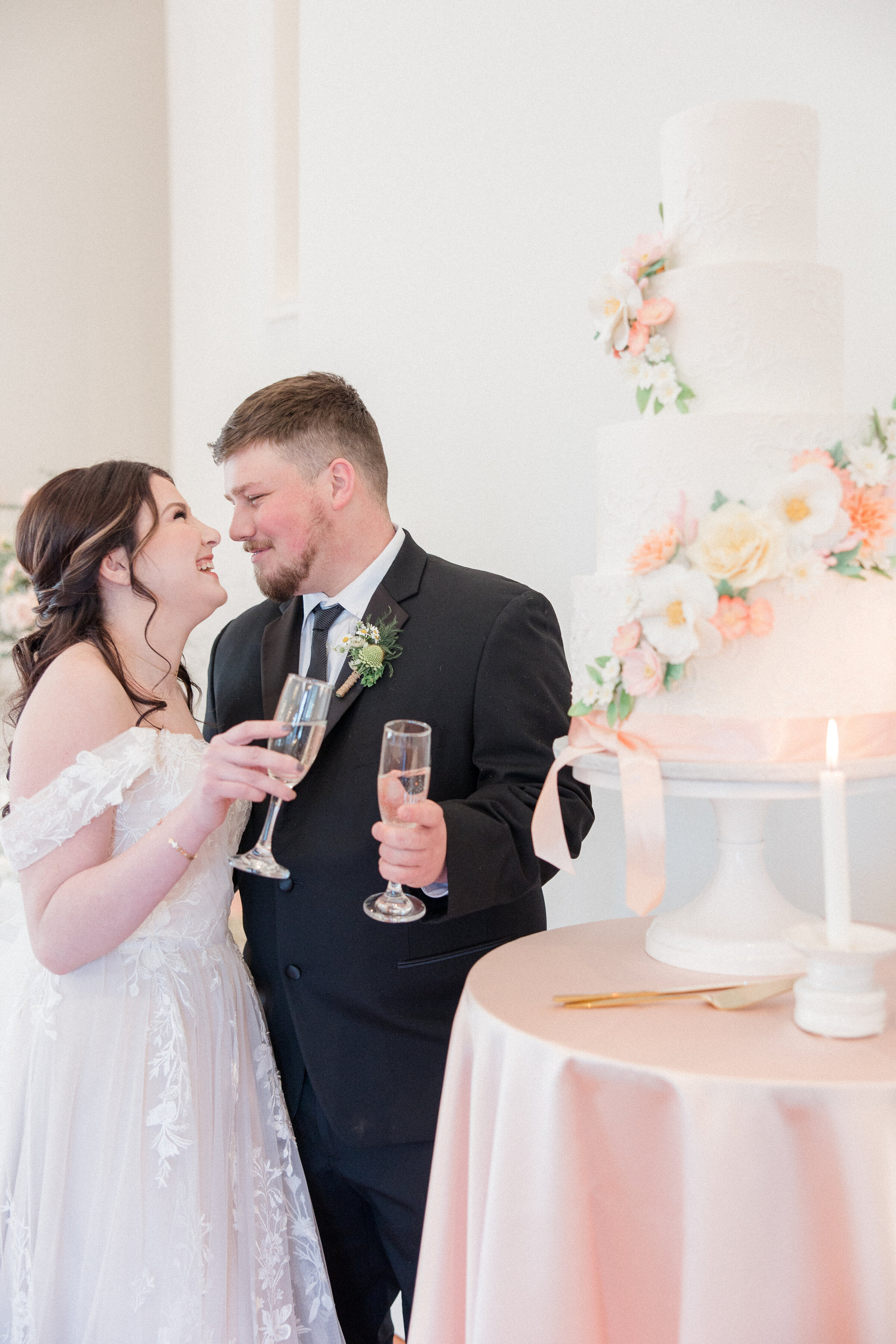 bride and groom clinking glasses at cake table