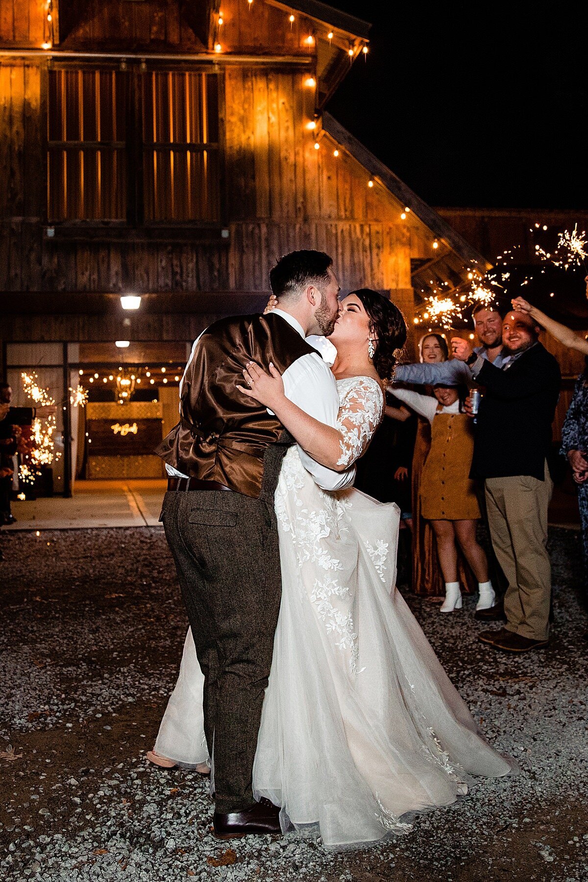 Bride and groom kissing during grand sparkler exit outside of Copper Ridge barn event center at night
