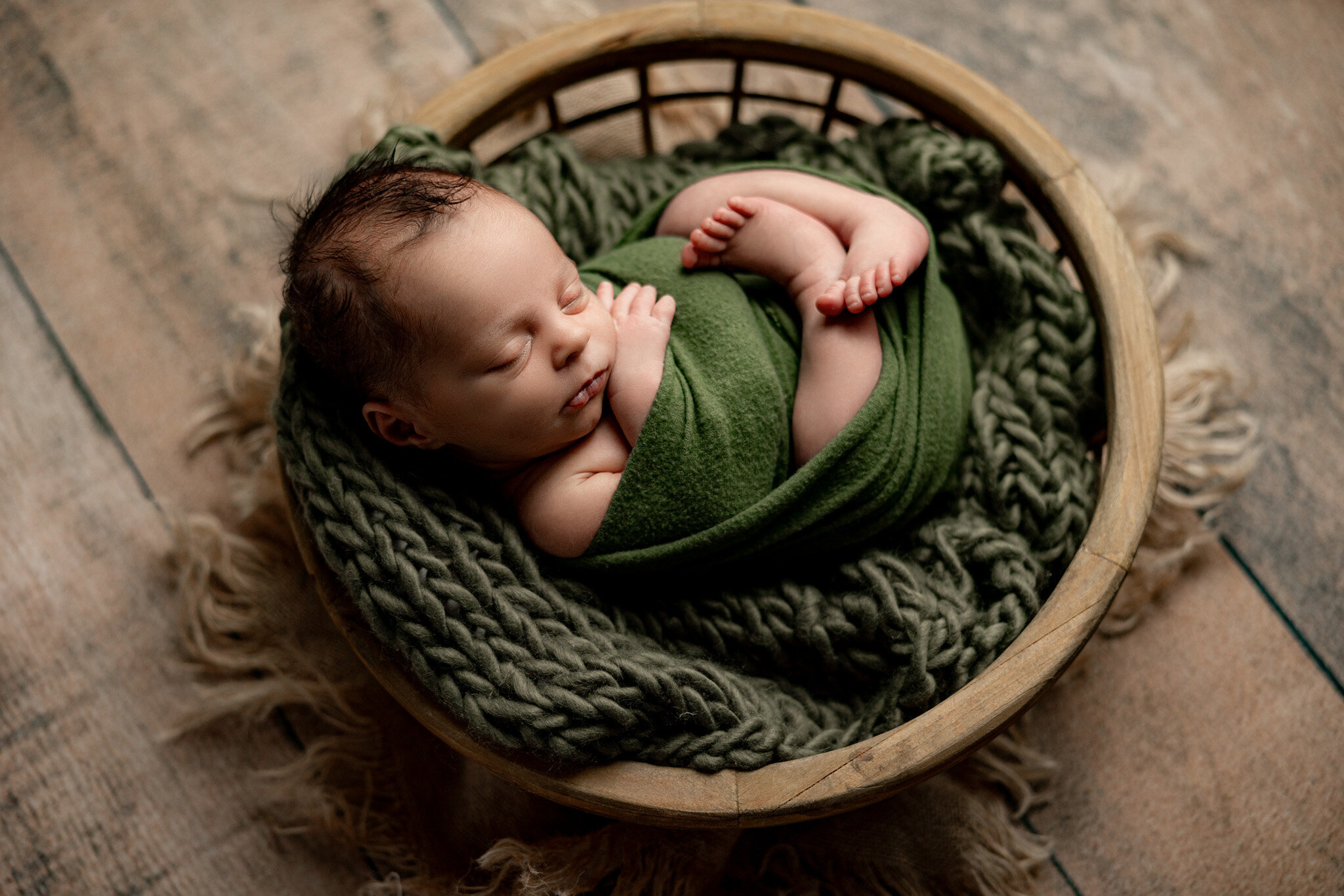 newborn baby wrapped in soft swaddle sleeping in Charlevoix during newborn session