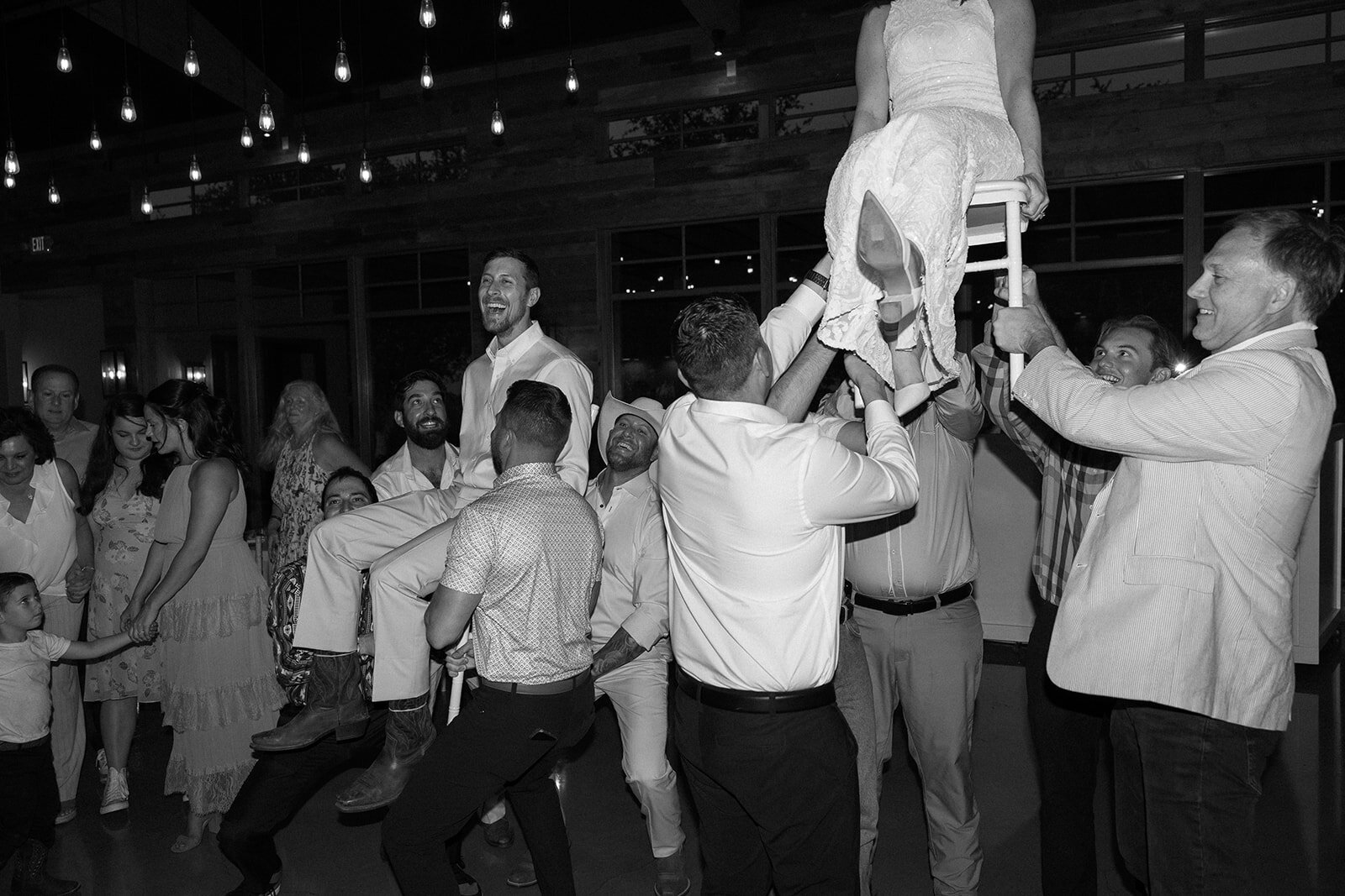 bride and groom in chairs as their guests lift them up to the beat of the music.