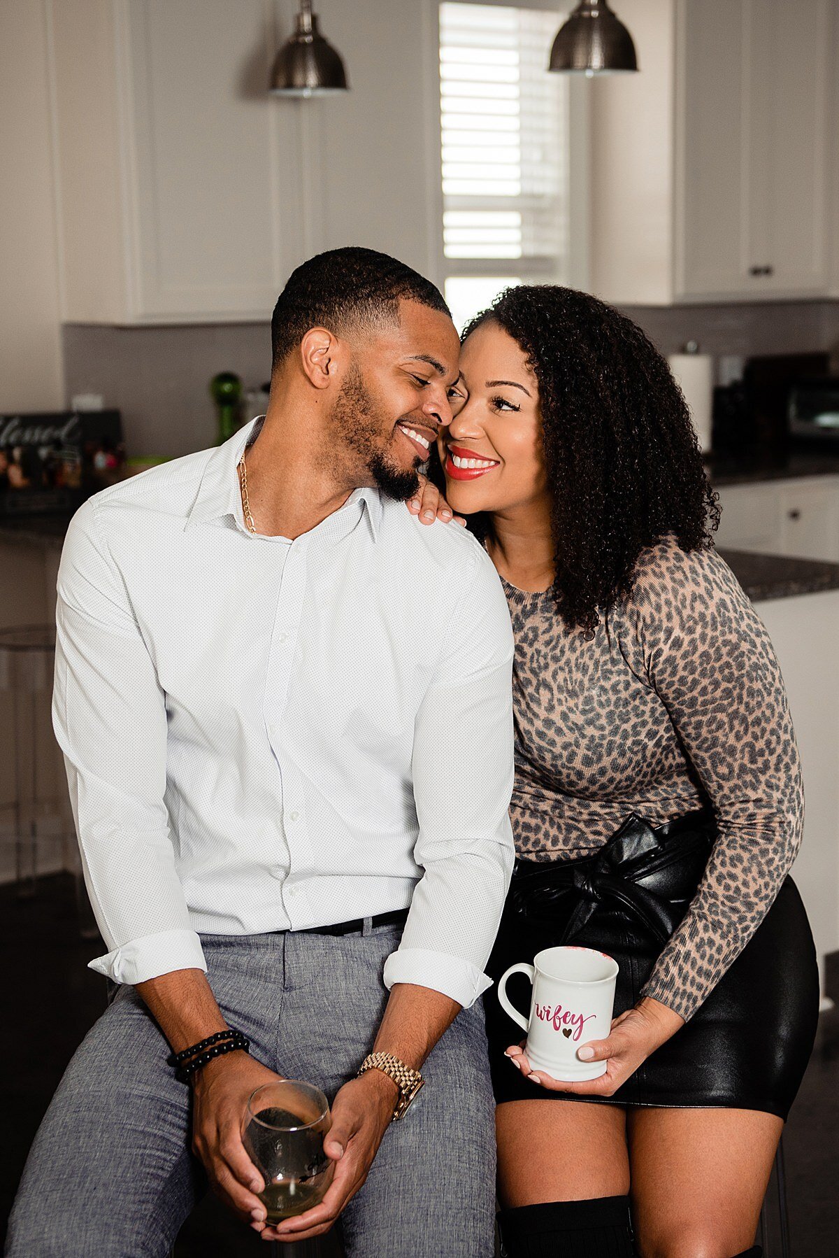 Couple holding coffee mugs and snuggled together in their new kitchen