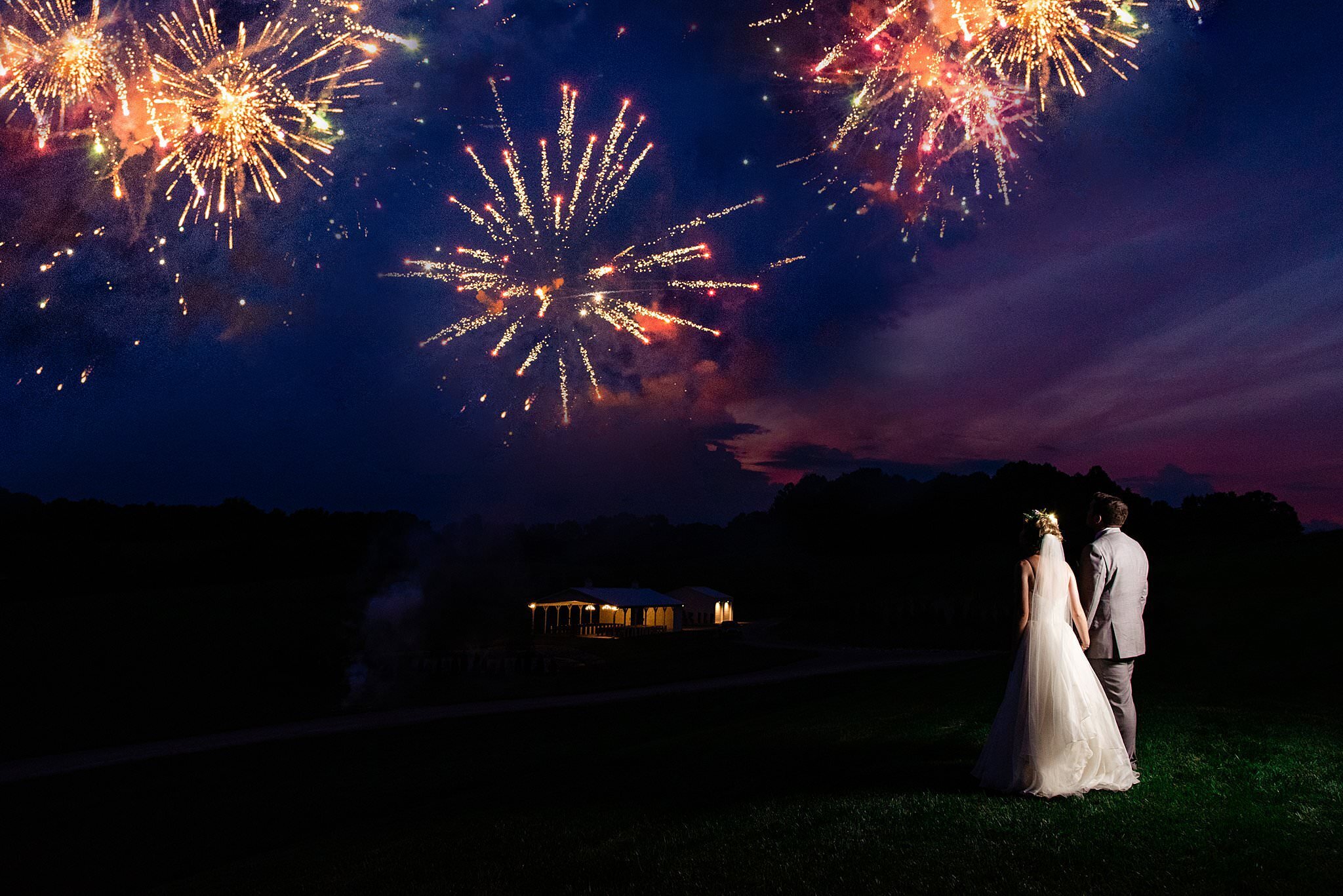 Bride and Groom watching fireworks at sunset outside White Dove Barn