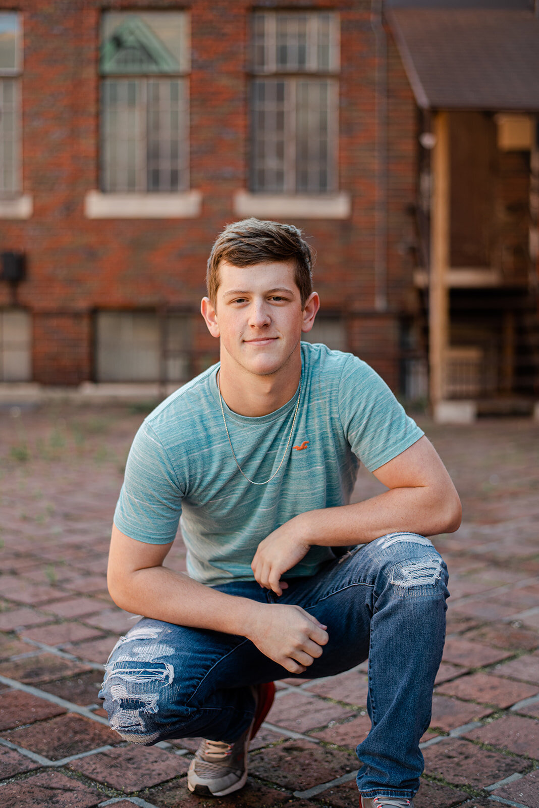 Senior boy sitting on a brick ledge in front of an old building in York, PA