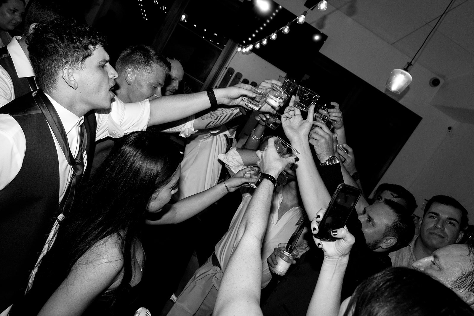 reception photo cheering and taking a shot, hands up in the air.