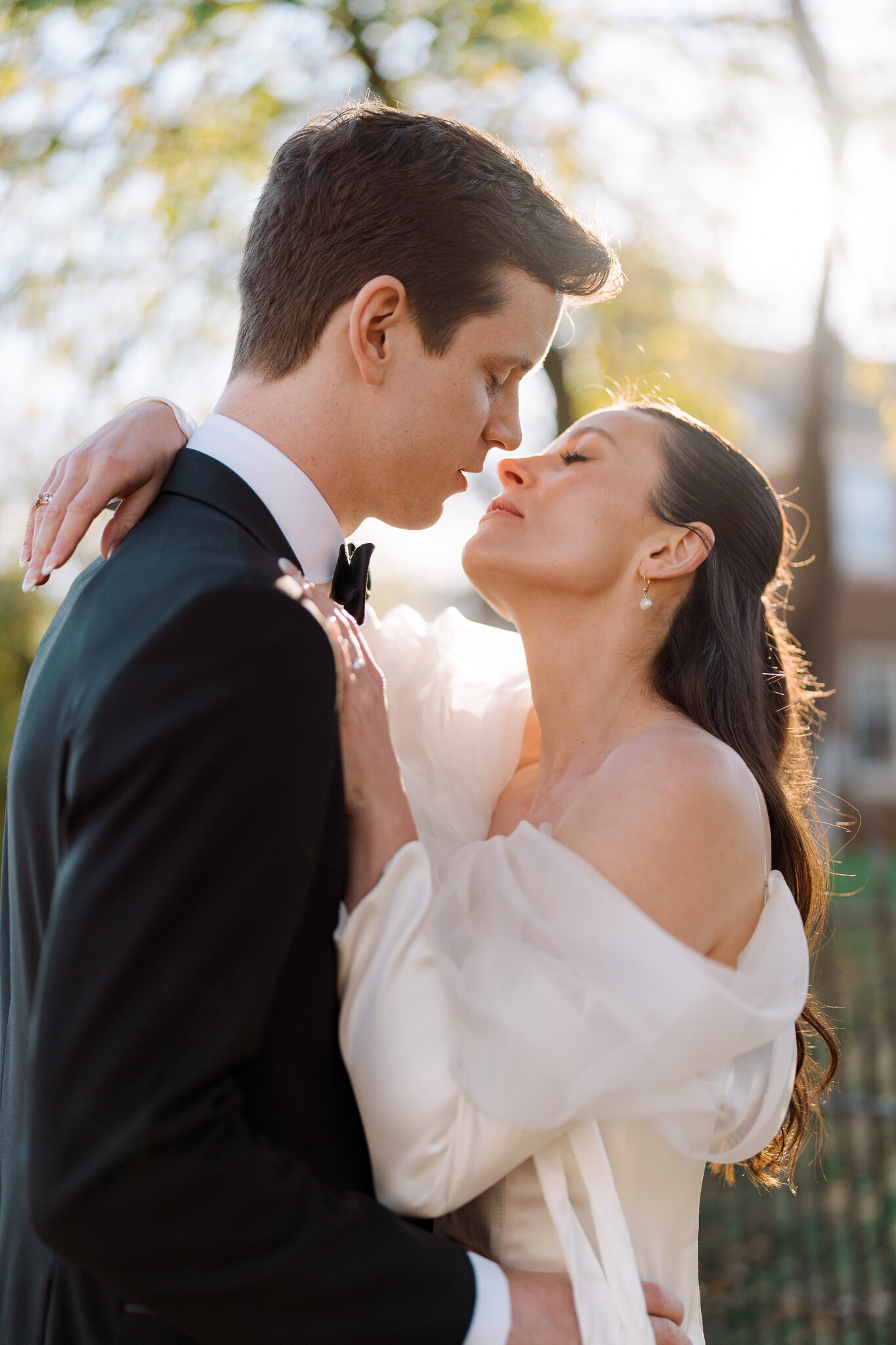 Bride and groom embrace in golden light, sharing a tender moment