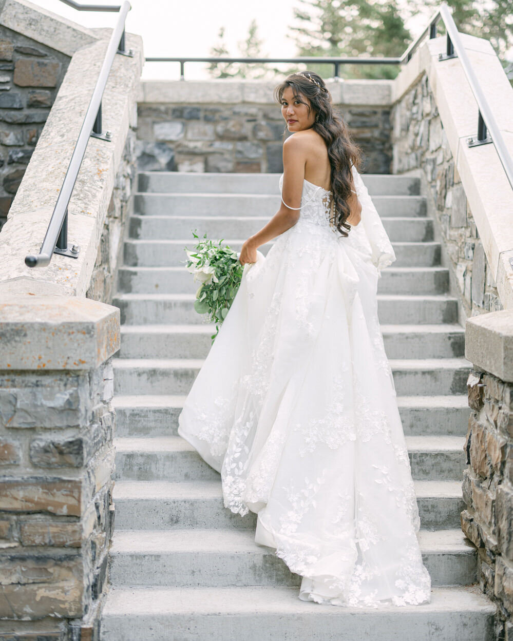This elegant bridal portrait captures the bride gracefully walking up the famous steps of the Banff Springs Hotel on her wedding day. The historic backdrop and her poised demeanor create a timeless and stunning moment.