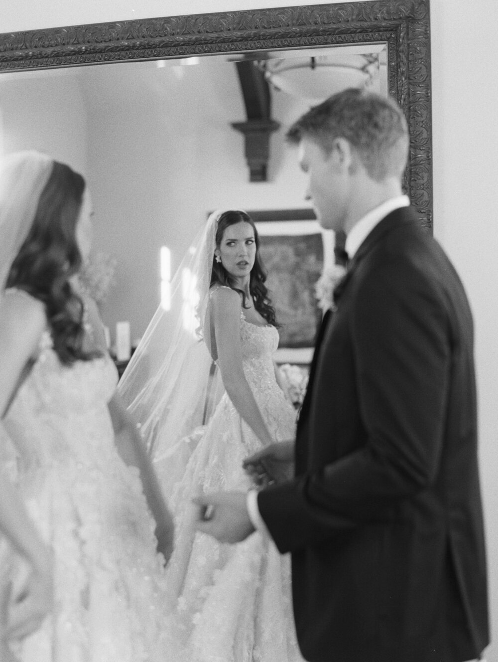 black and white film photo of bride and groom candid looking into mirror