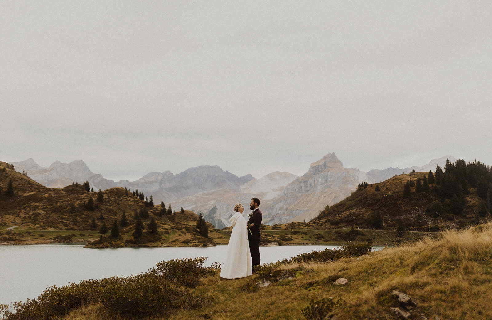 A wedding couple at Trübsee in central Switzerland on their wedding day. Beautiful lake and mountains in the background.