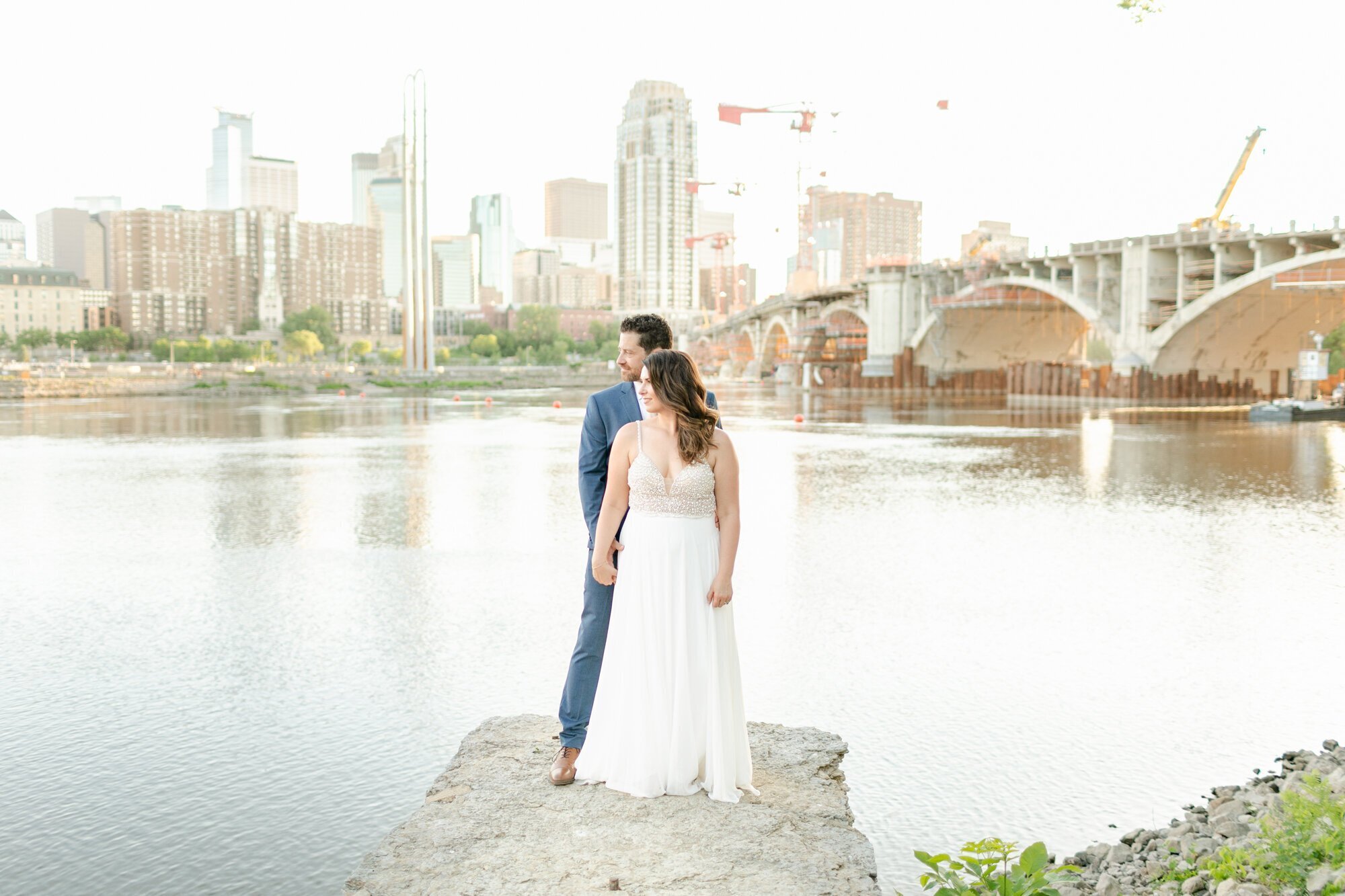 Bride and groom on a rock in front of a bridge, taken by wedding photographer minneapolis