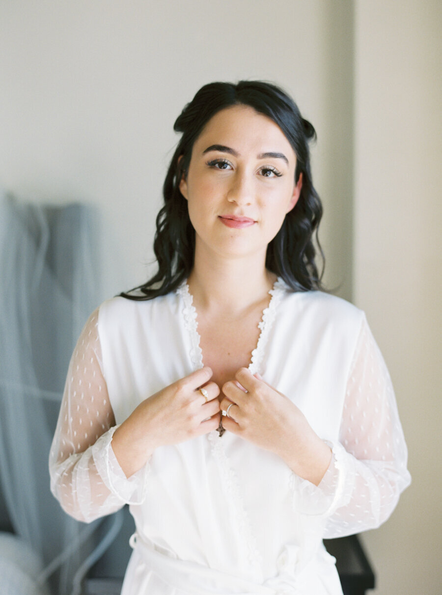 bride in white lace robe looking intently into camera
