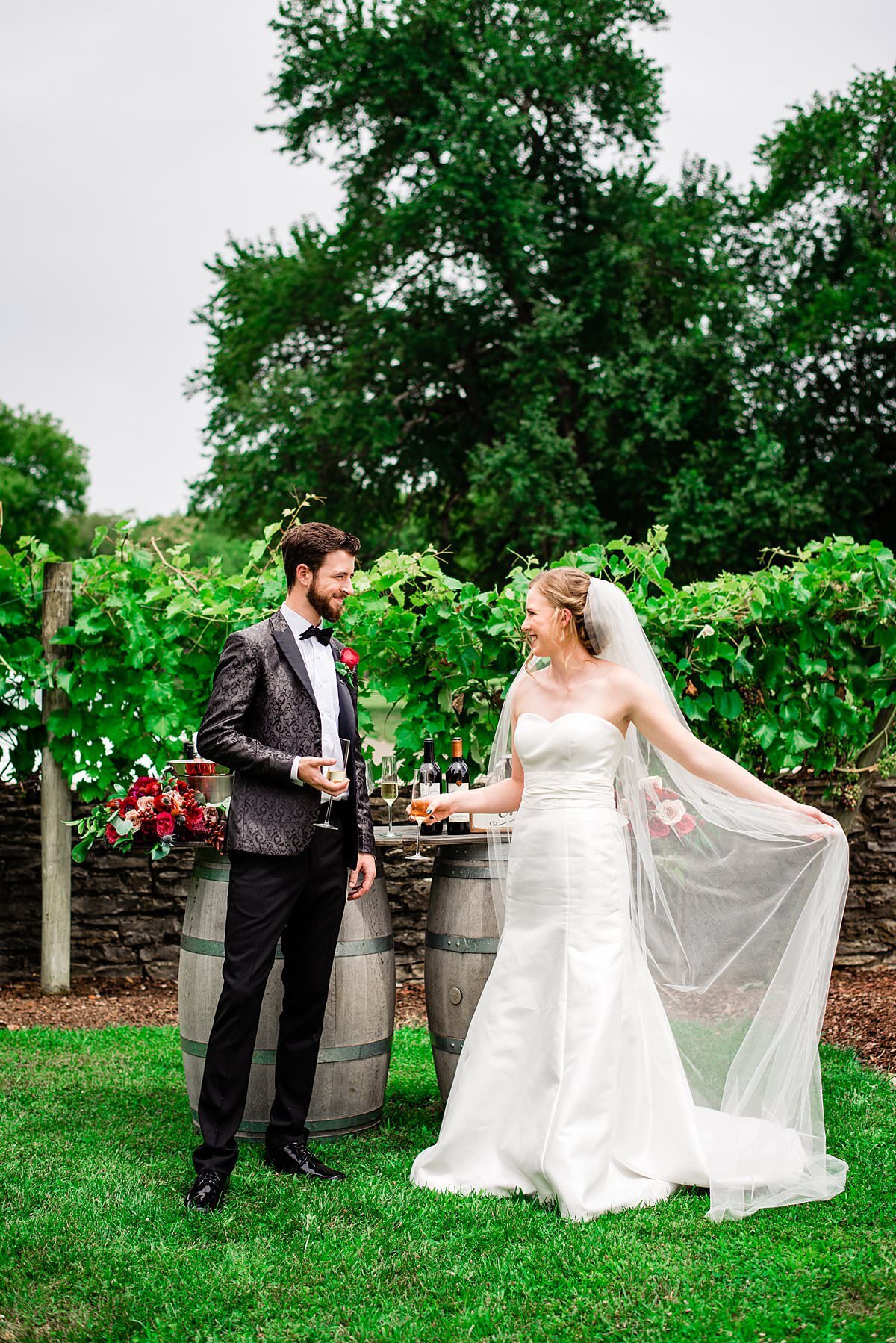 Newlyweds standing next to wine bar on a summer day next to the green vineyards