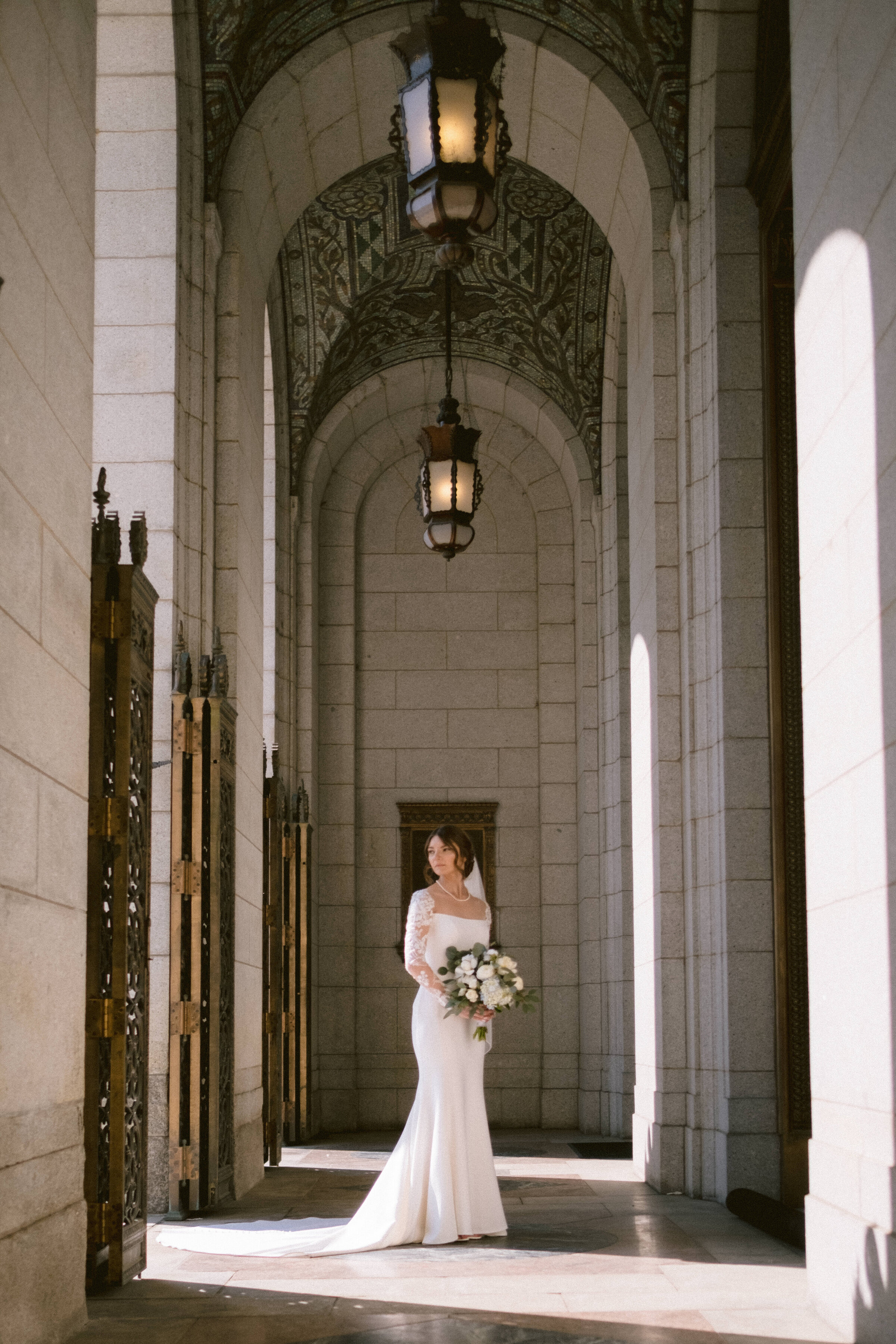 Bride stands elegantly in a grand architectural archway