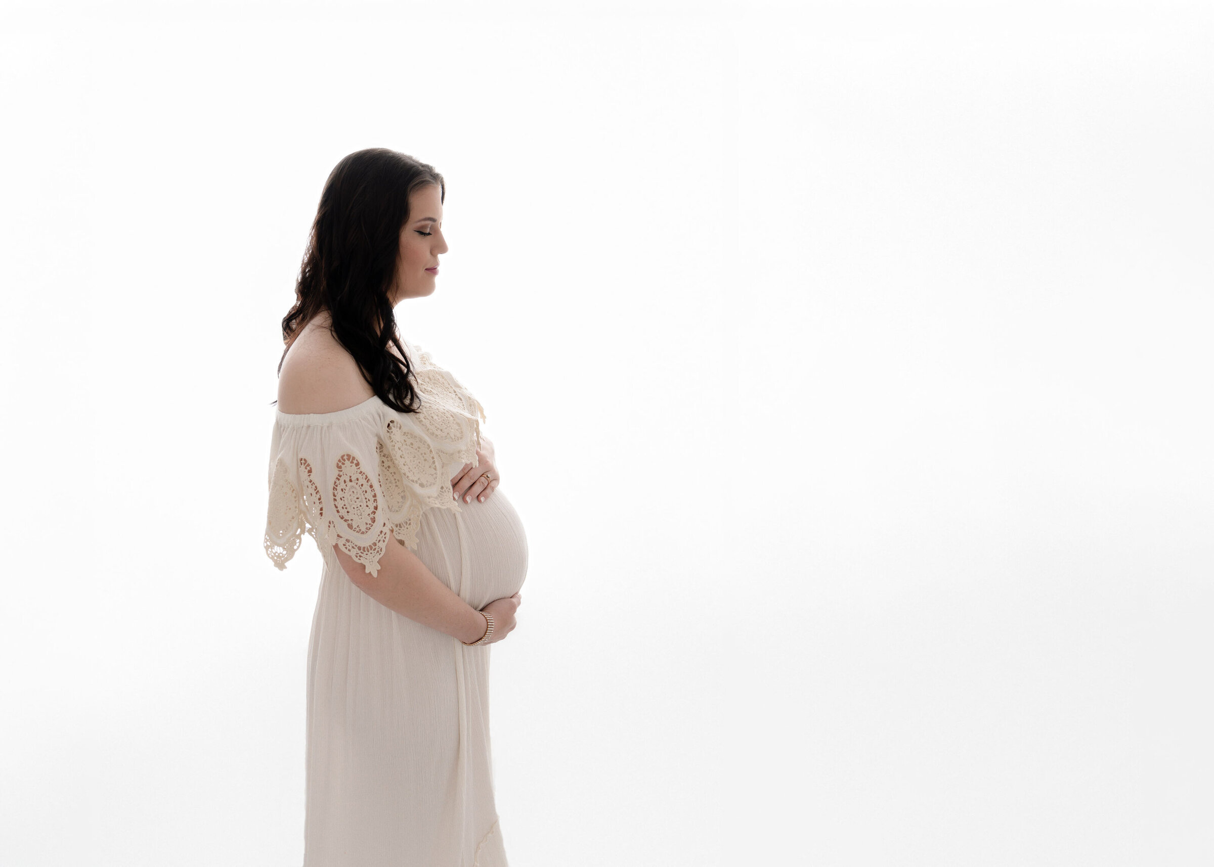 Profile of newborn baby girl sleeping on her side wearing a white lace bonnet