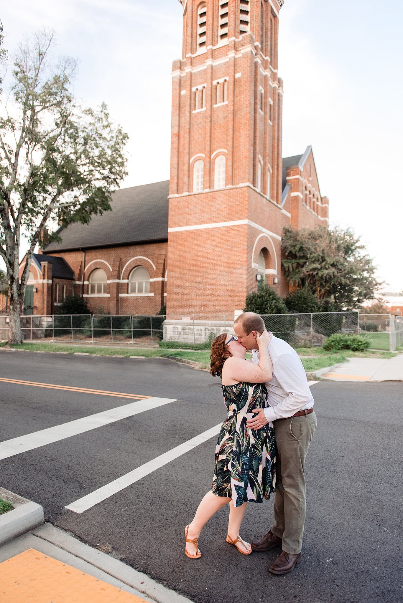 Couple sharing a romantic kiss in the crosswalk outside of a historic downtown Murfreesboro church