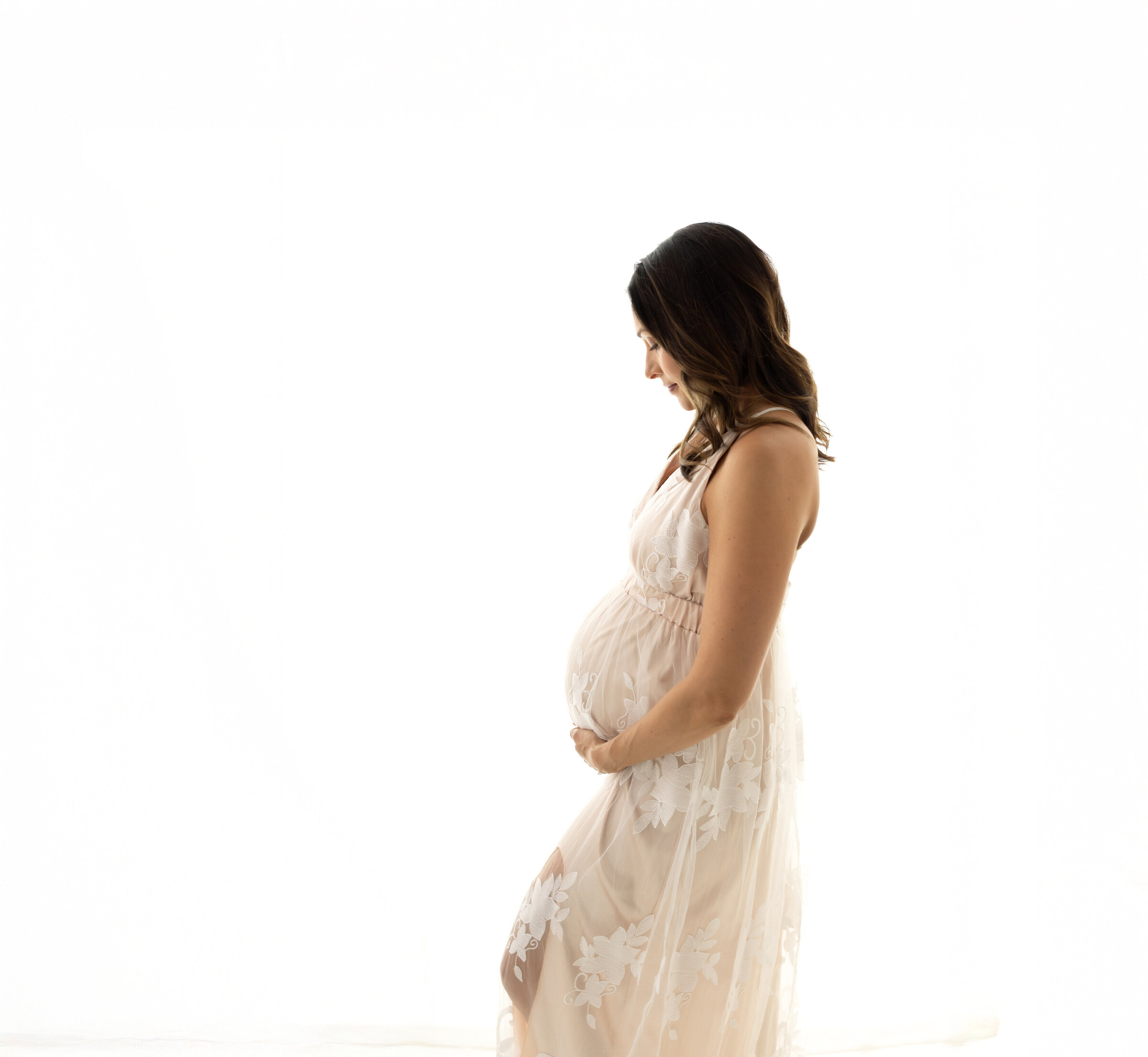 pregnant mother in cream maternity gown holding baby bump for maternity photos