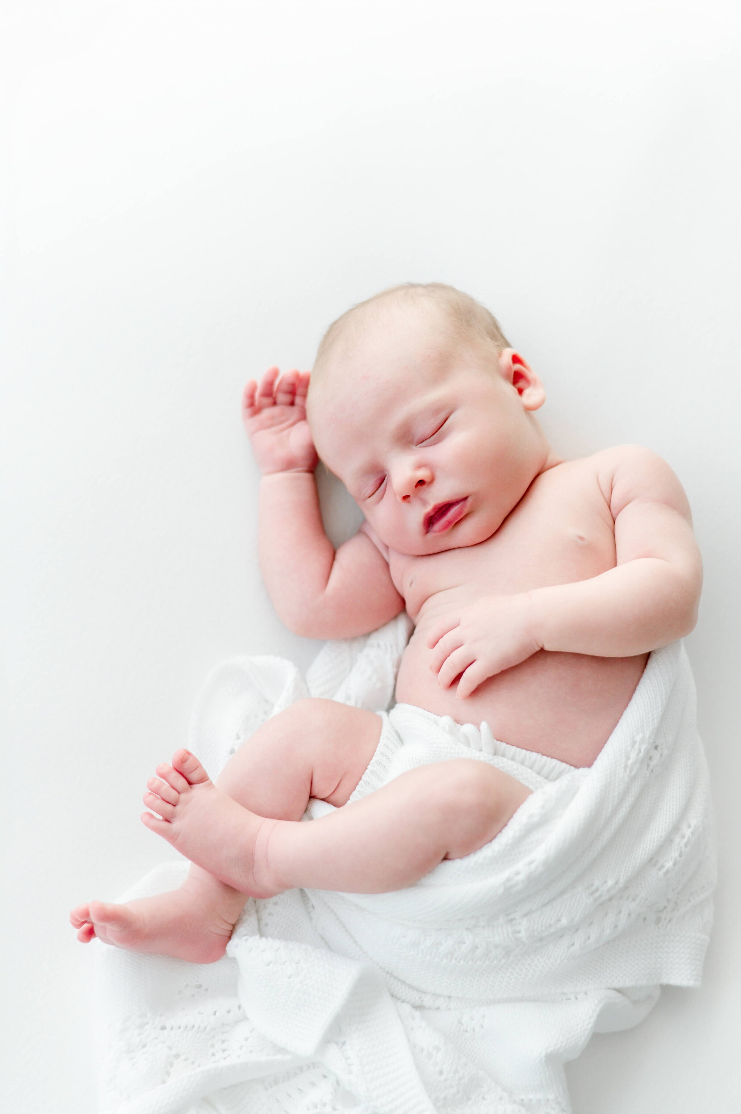 Unposed, sleeping newborn on white bean bag  in Kristie Lloyd's Nashville newborn photography studio